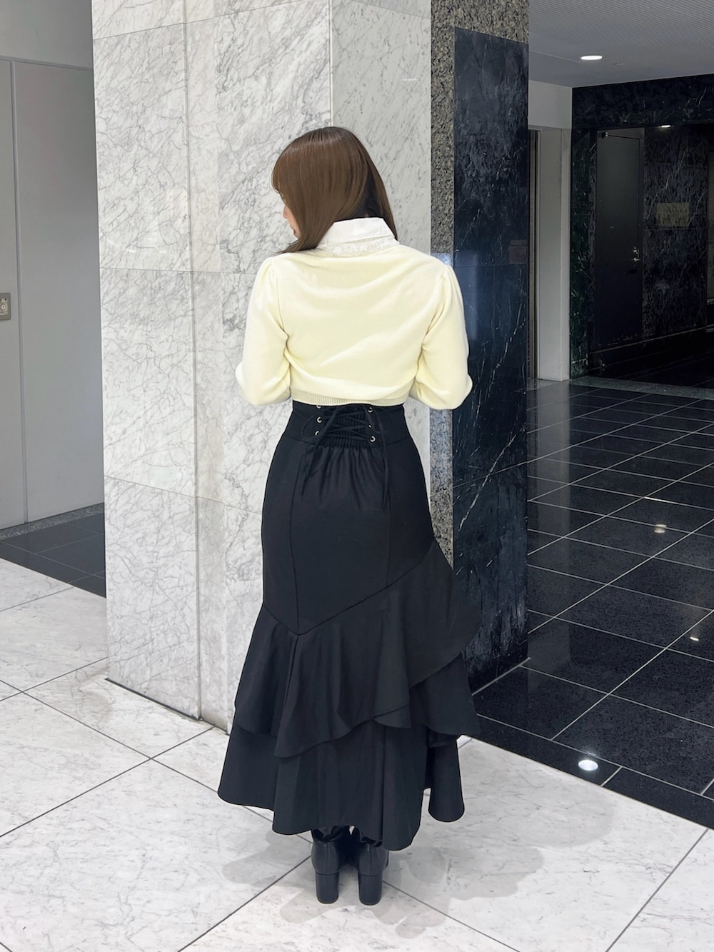 ホワイト系のニット/セーター、ブラック系のスカート、ブラック系のブーツを着用したレディースの秋コーディネートの4枚目の写真