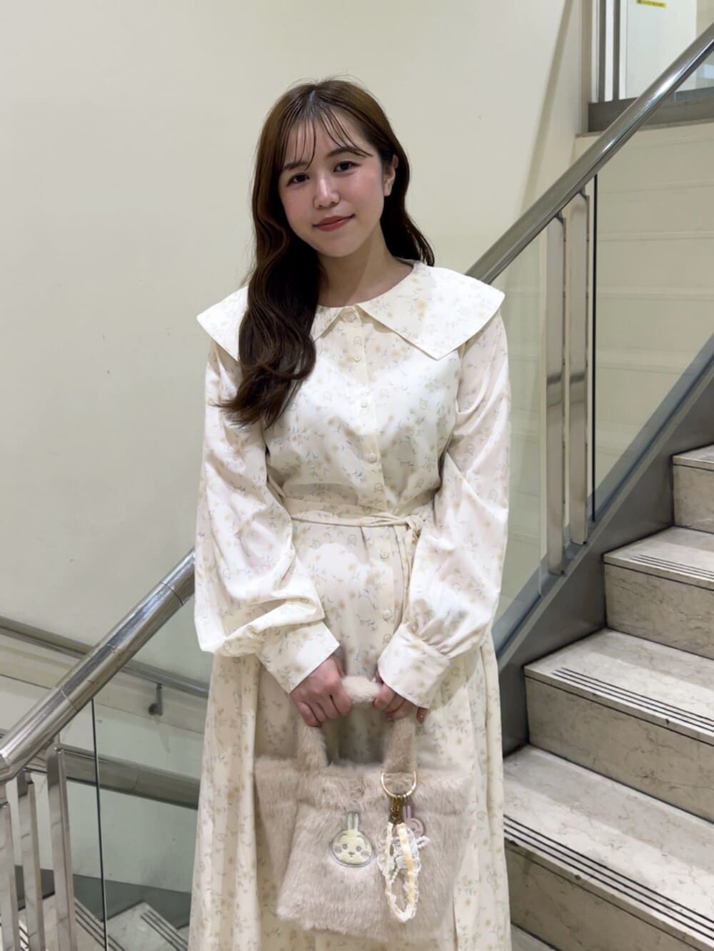 イエロー系のワンピース、イエロー系のハンドバッグ、ホワイト系のパンプスを着用したレディースの秋コーディネートの5枚目の写真