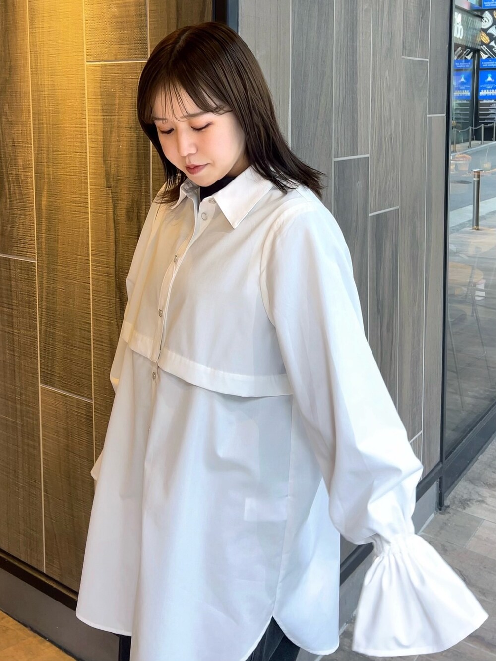 ホワイト系のワンピース、ブラック系のデニムパンツ、ブラック系のブーツを着用したレディースの春コーディネートの4枚目の写真