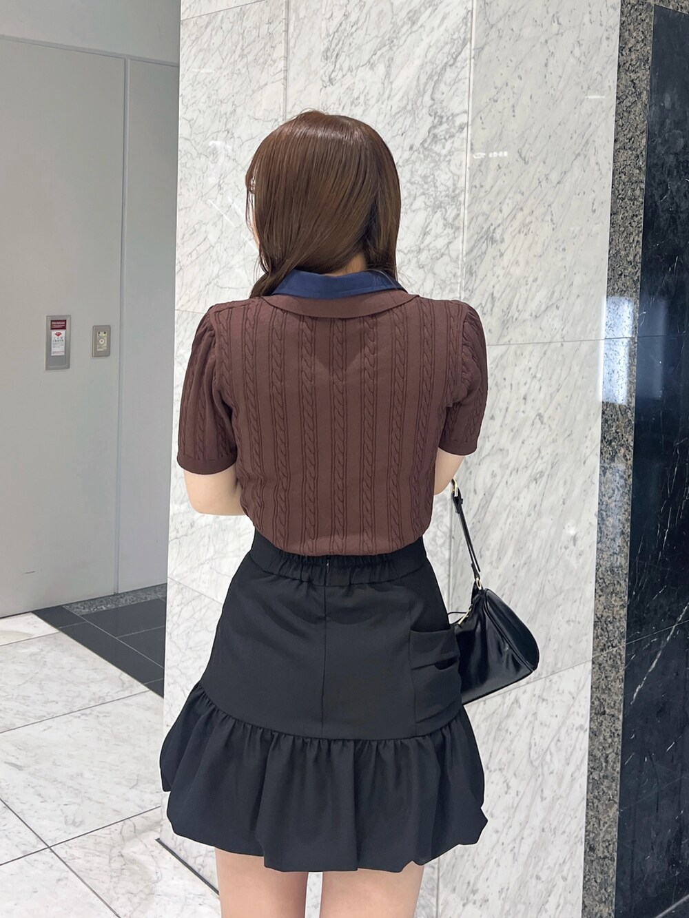 ブラウン系のニット/セーター、ブラック系のスカート、ブラック系のサンダルを着用したレディースの夏コーディネートの6枚目の写真