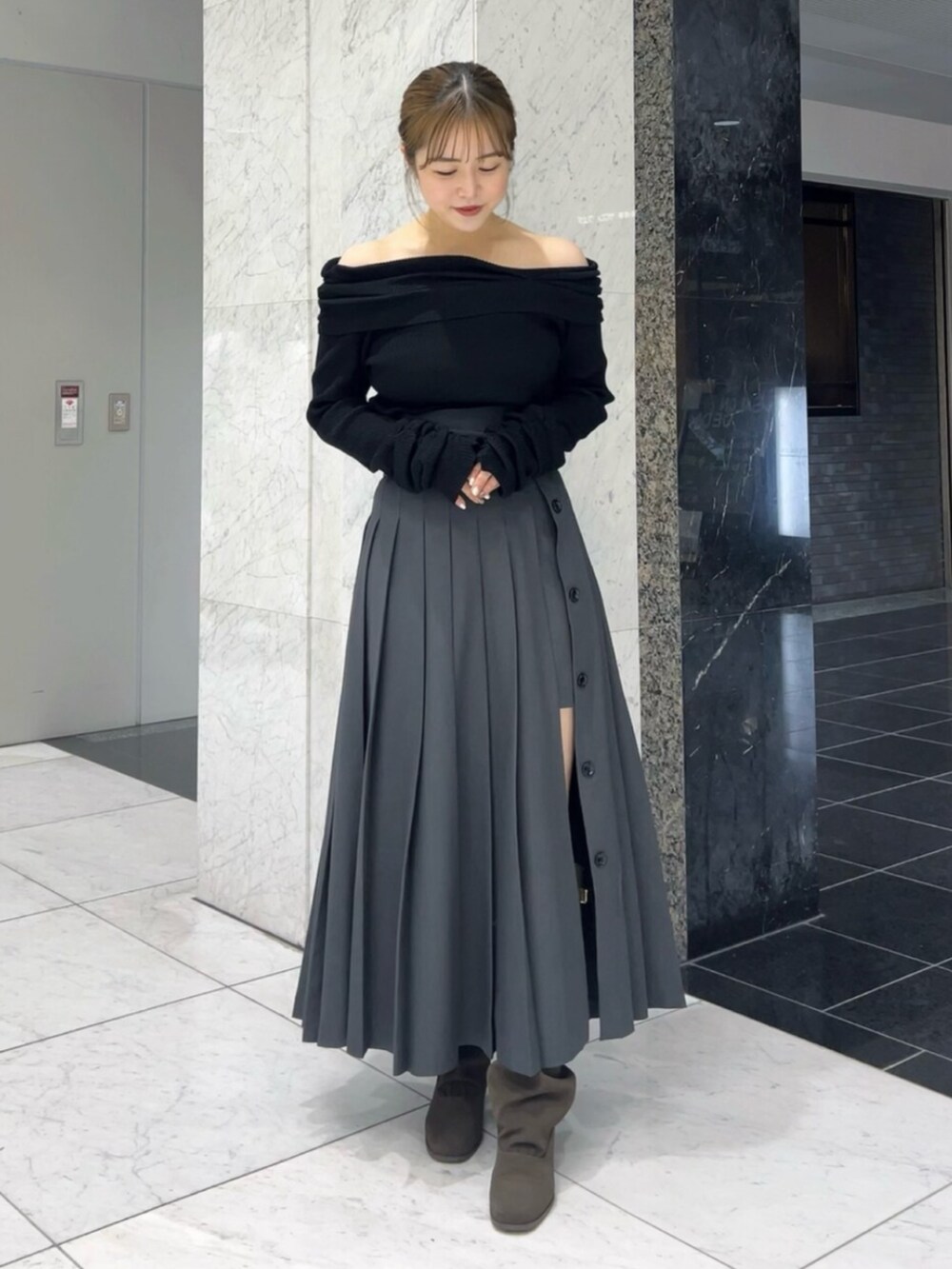 ブラック系のニット/セーター、グレー系のスカート、ブラウン系のブーツを着用したレディースの秋コーディネートの2枚目の写真