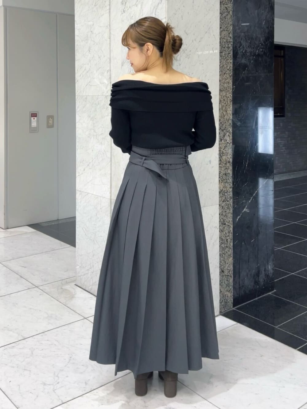 ブラック系のニット/セーター、グレー系のスカート、ブラウン系のブーツを着用したレディースの秋コーディネートの3枚目の写真