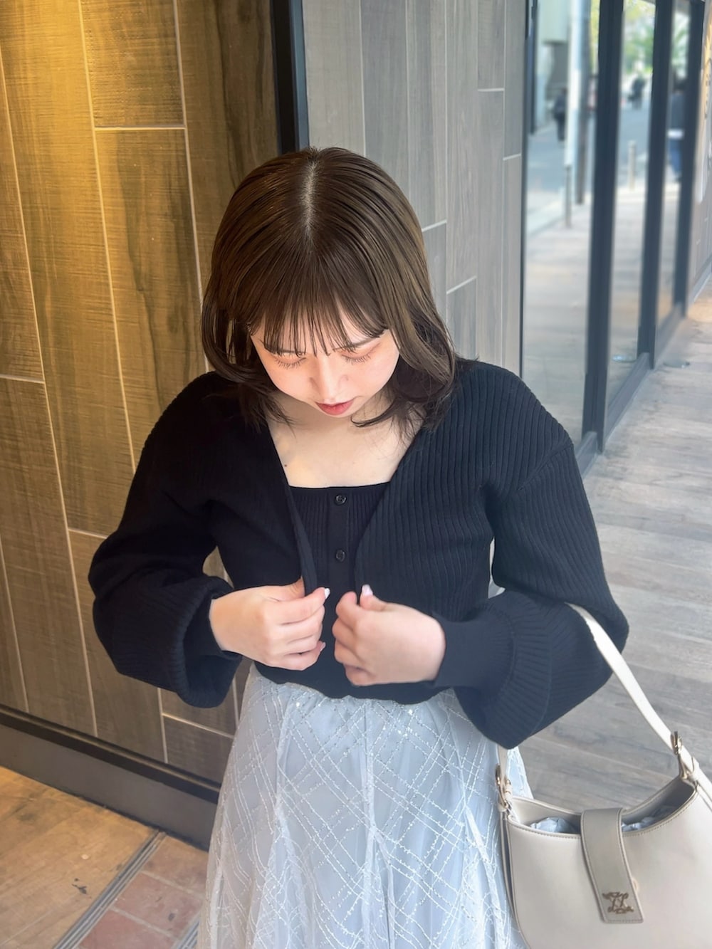 ブラック系のアンサンブル、グレー系のスカート、ホワイト系のパンプスを着用したレディースの春コーディネートの7枚目の写真