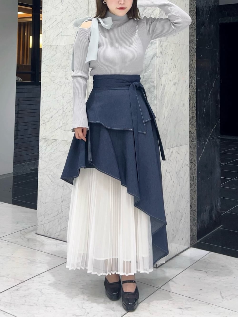 グレー系のニット/セーター、ブルー系のスカート、ブラック系のパンプスを着用したレディースの秋コーディネートの3枚目の写真