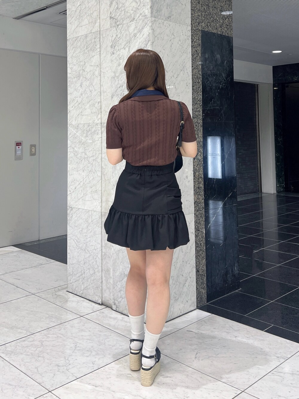 ブラウン系のニット/セーター、ブラック系のスカート、ブラック系のサンダルを着用したレディースの夏コーディネートの4枚目の写真