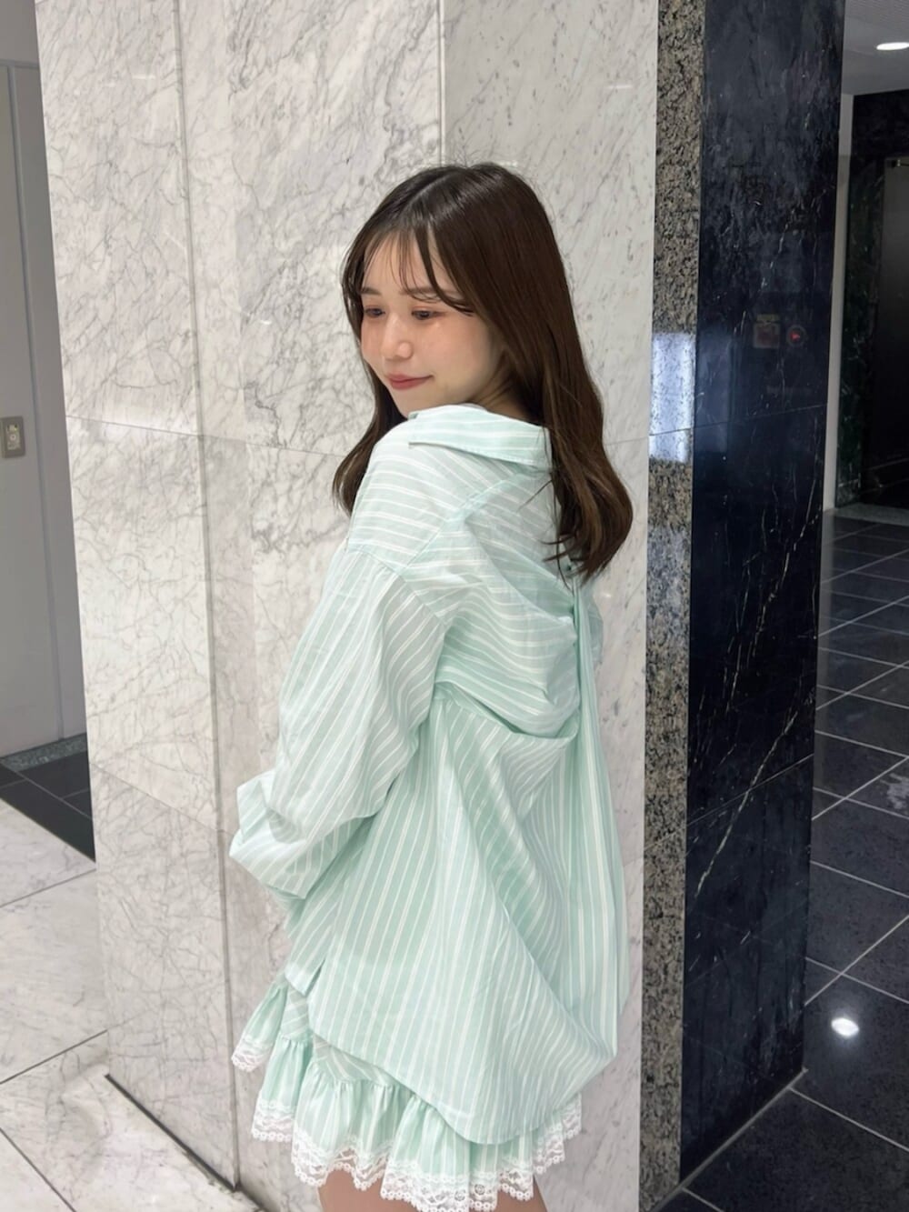 グリーン系のシャツ/ブラウス、グリーン系のスカート、ブラウン系のブーツを着用したレディースの春コーディネートの6枚目の写真