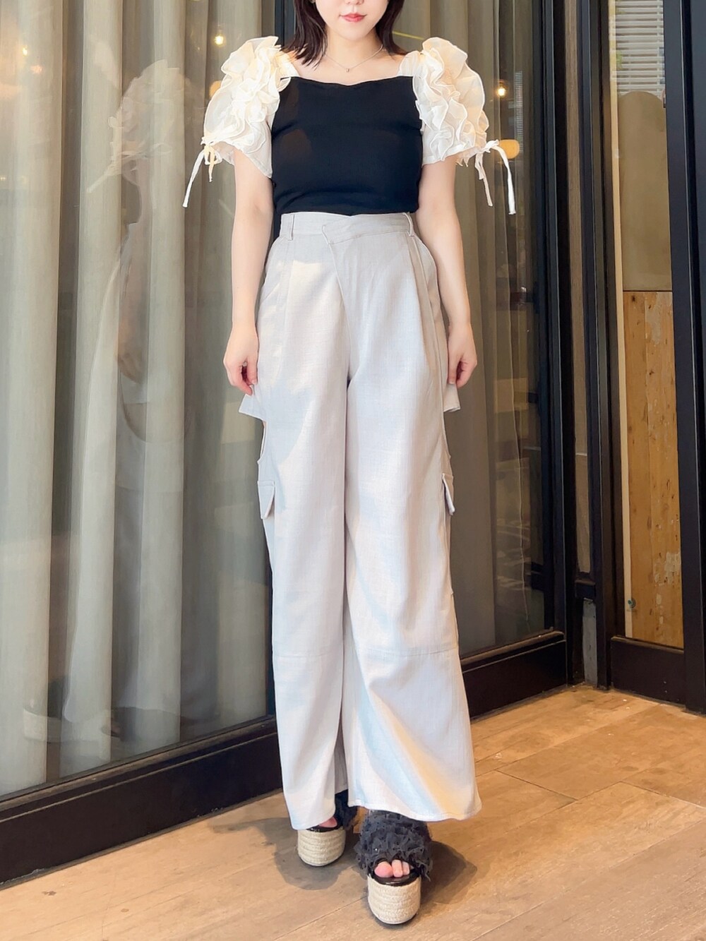 ブラック系のTシャツ/カットソー、グレー系のチノパンツ、ブラック系のサンダルを着用したレディースの夏コーディネートの3枚目の写真