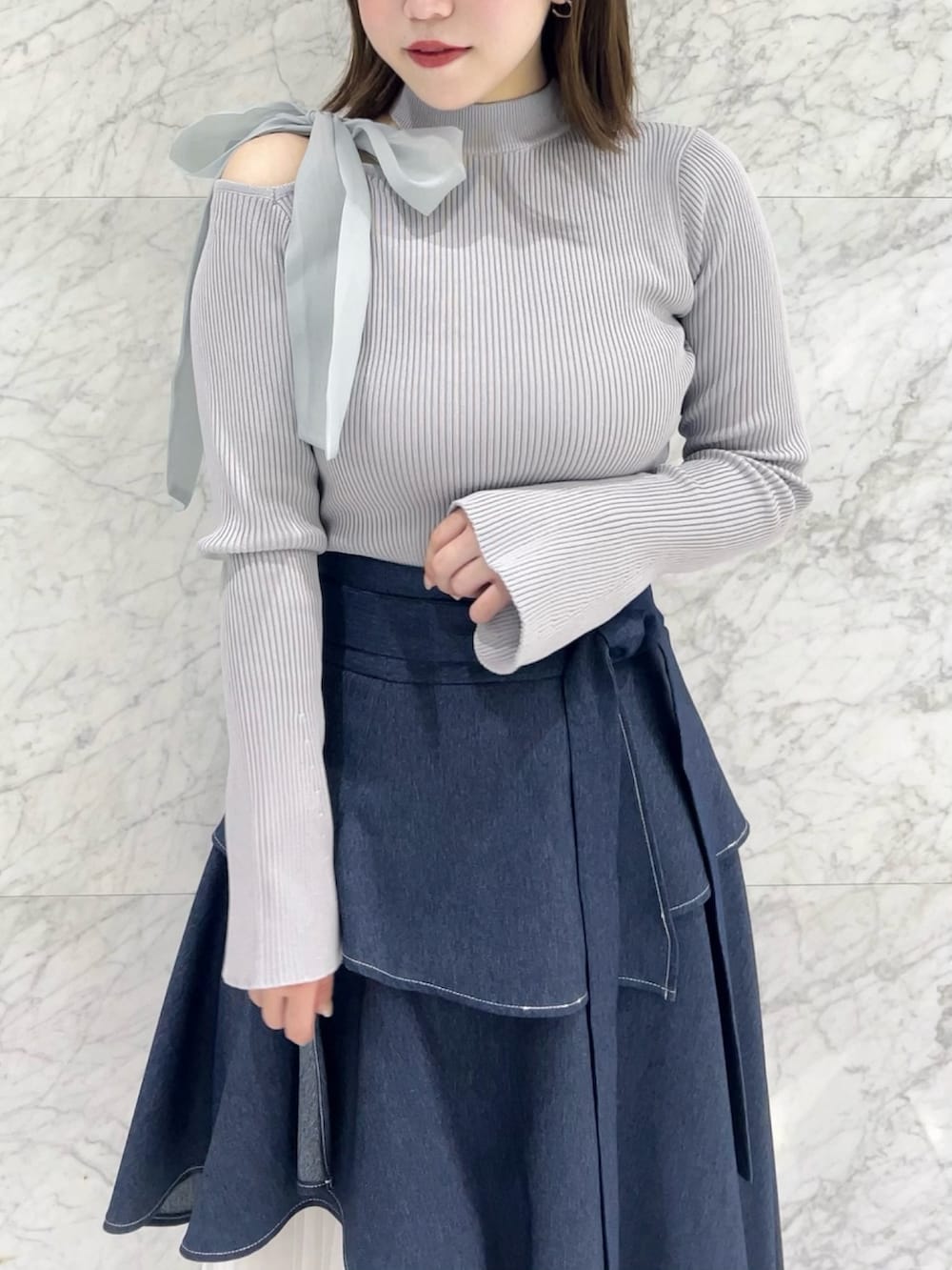 グレー系のニット/セーター、ブルー系のスカート、ブラック系のパンプスを着用したレディースの秋コーディネートの5枚目の写真