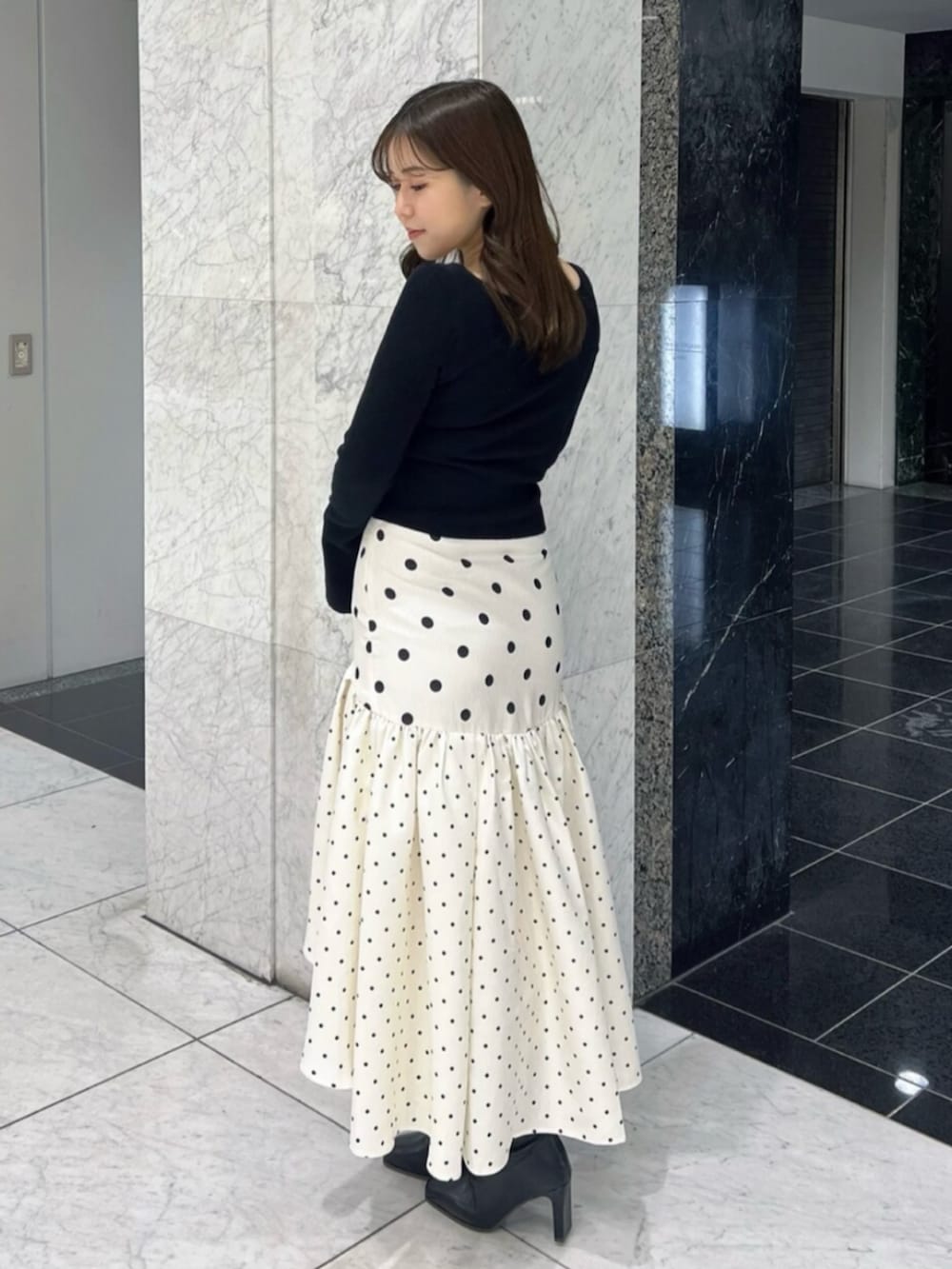 ブラック系のブーツ、ブラック系のニット/セーター、ホワイト系のスカートを着用したレディースの春コーディネートの3枚目の写真