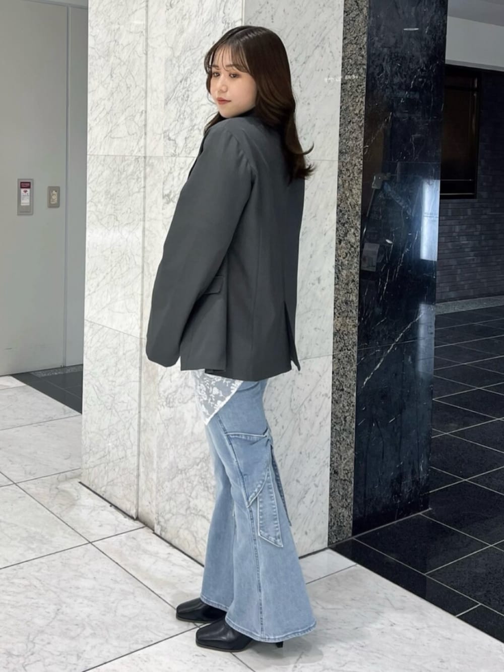 ブラック系のニット/セーター、ブラック系のブーツ、グレー系のテーラードジャケットを着用したレディースの冬コーディネートの2枚目の写真