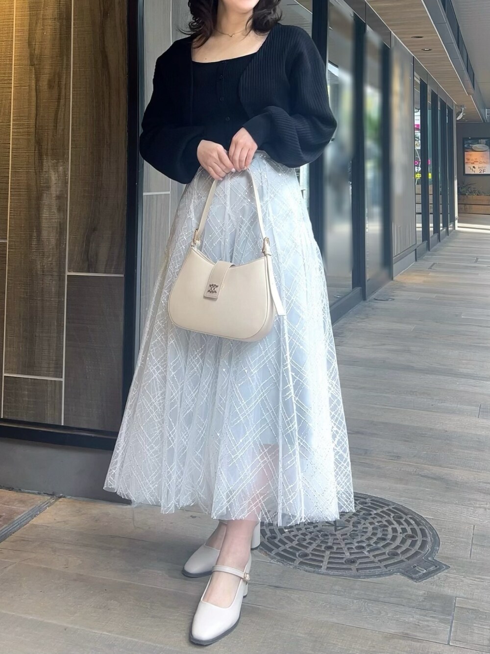 ブラック系のアンサンブル、グレー系のスカート、ホワイト系のパンプスを着用したレディースの春コーディネートの5枚目の写真