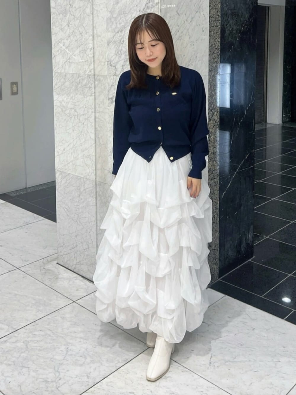 ブルー系のカーディガン/ボレロ、ホワイト系のスカート、ホワイト系のブーツを着用したレディースの秋コーディネートの3枚目の写真