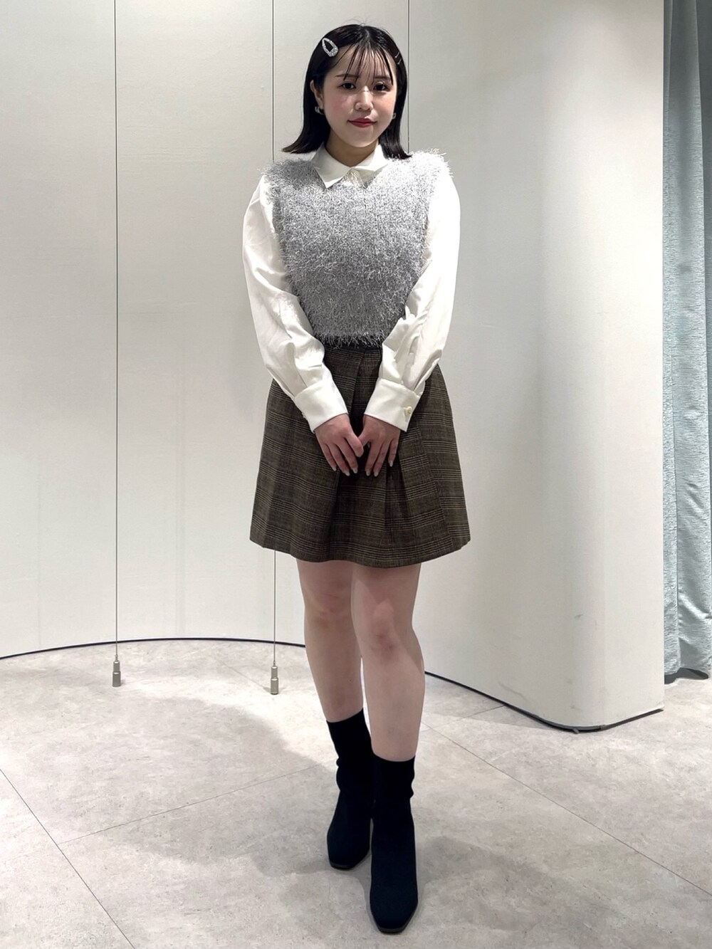グレー系のニット/セーター、ホワイト系のシャツ/ブラウス、ブラウン系のスカートを着用したレディースの秋コーディネートの2枚目の写真