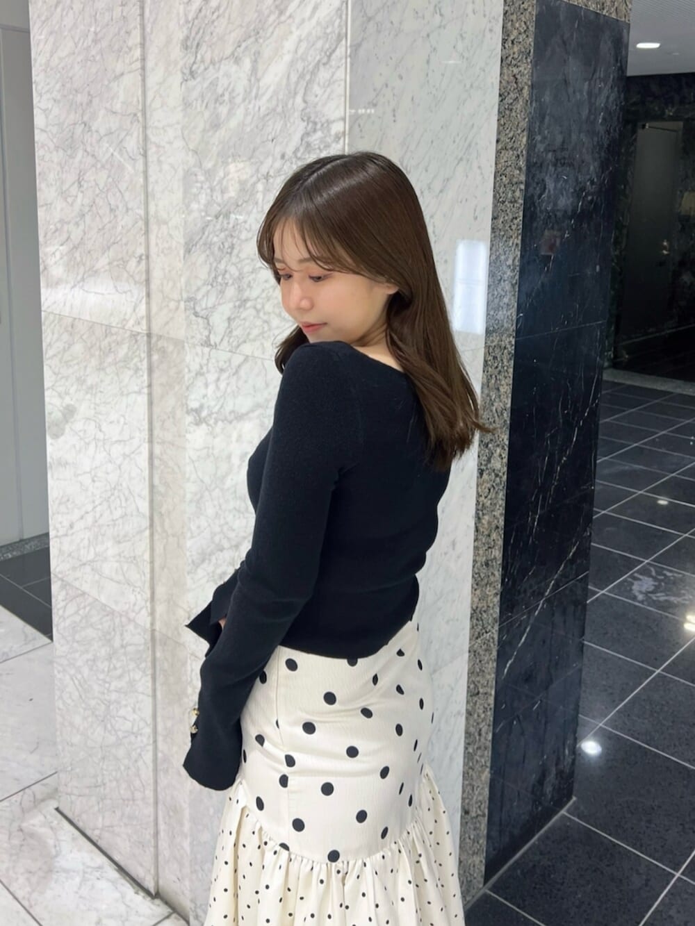 ブラック系のブーツ、ブラック系のニット/セーター、ホワイト系のスカートを着用したレディースの春コーディネートの6枚目の写真