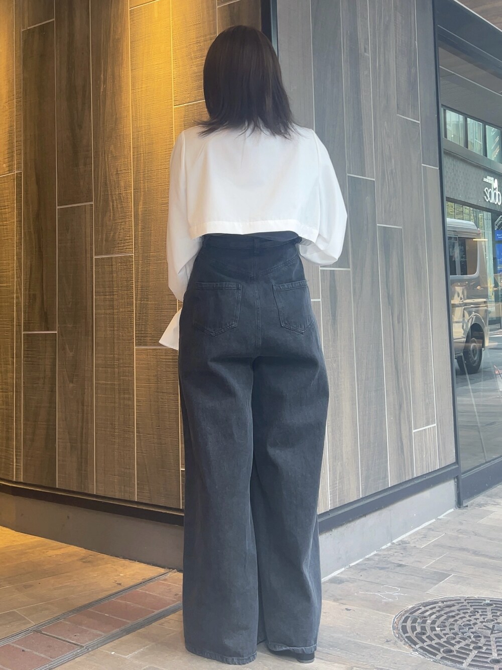 ホワイト系のワンピース、ブラック系のデニムパンツ、ブラック系のブーツを着用したレディースの春コーディネートの7枚目の写真