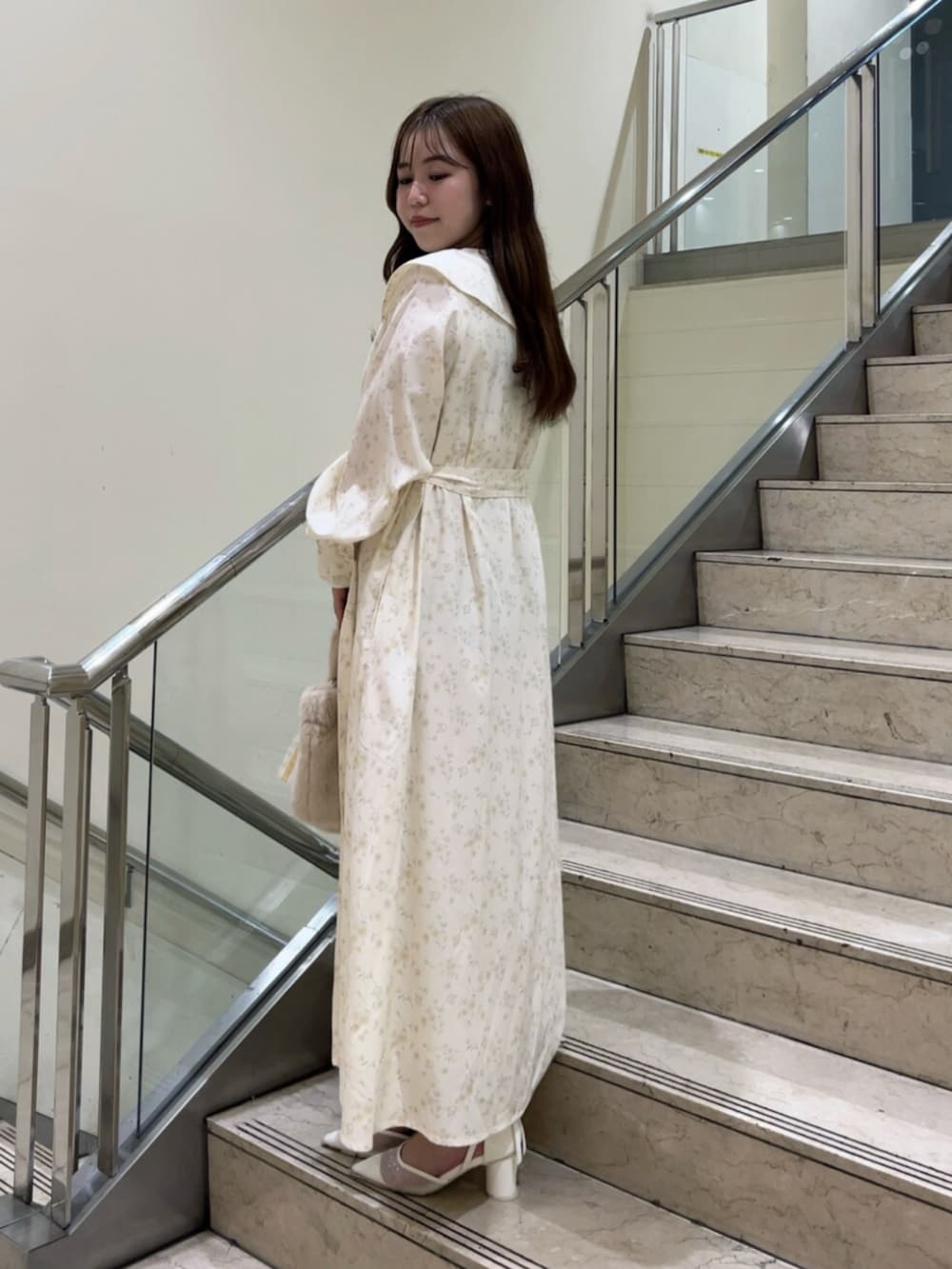 イエロー系のワンピース、イエロー系のハンドバッグ、ホワイト系のパンプスを着用したレディースの秋コーディネートの3枚目の写真