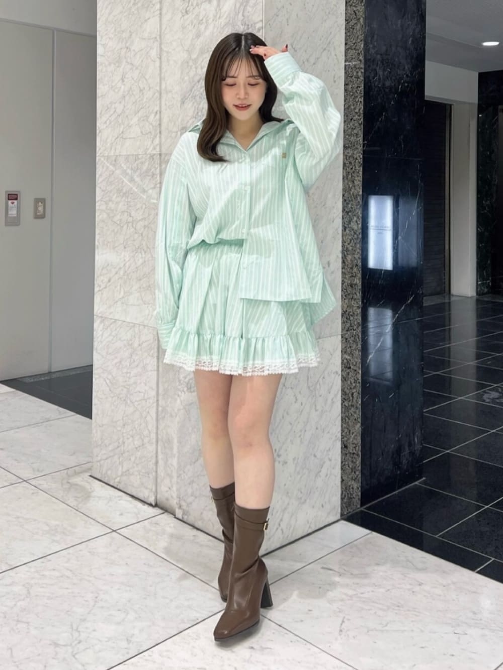 グリーン系のシャツ/ブラウス、グリーン系のスカート、ブラウン系のブーツを着用したレディースの春コーディネートの2枚目の写真