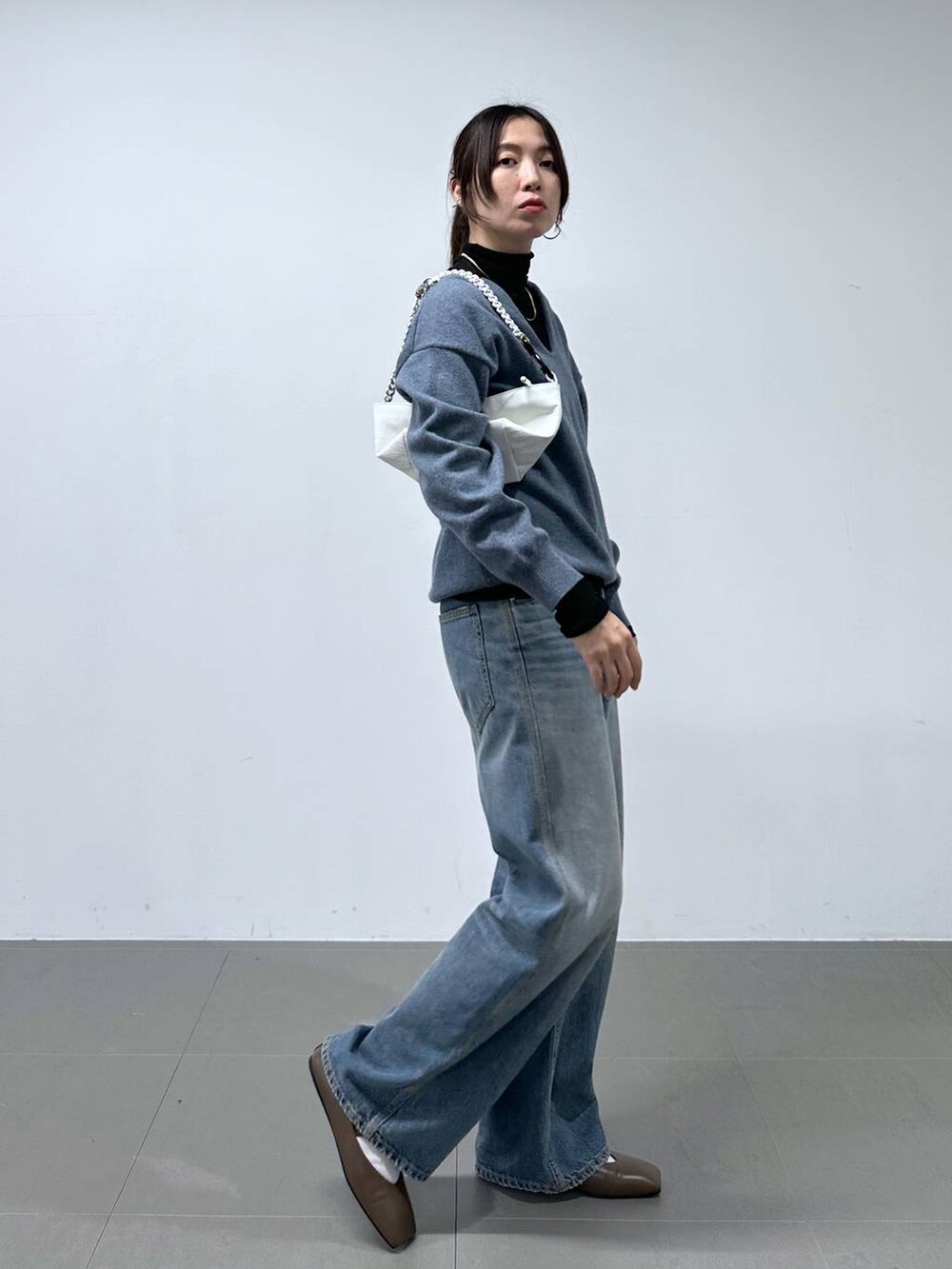 ブルー系のデニムパンツ、ホワイト系のショルダーバッグ、ブラック系のTシャツ/カットソーを着用したレディースの冬コーディネートの2枚目の写真