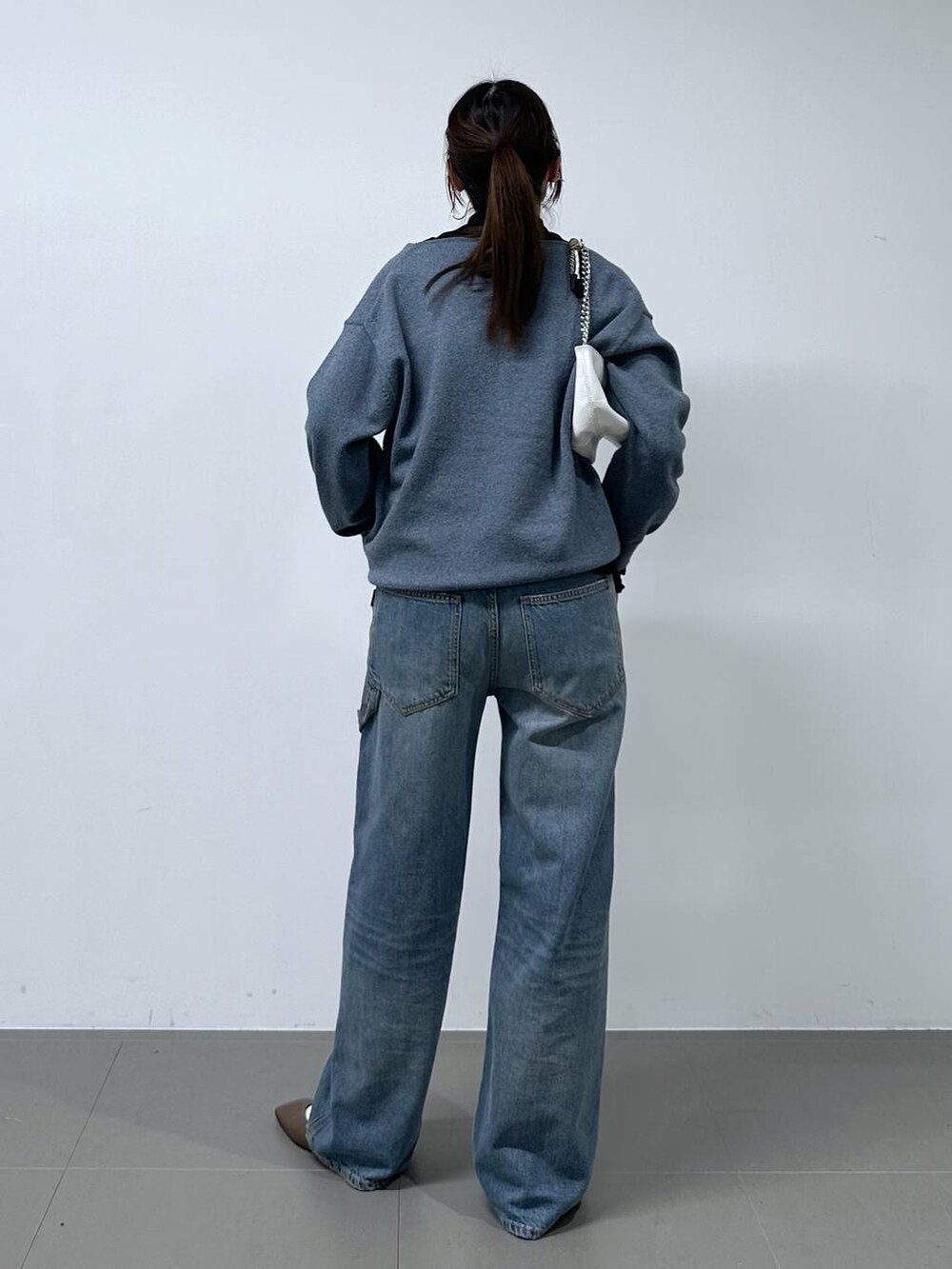 ブルー系のデニムパンツ、ホワイト系のショルダーバッグ、ブラック系のTシャツ/カットソーを着用したレディースの冬コーディネートの3枚目の写真