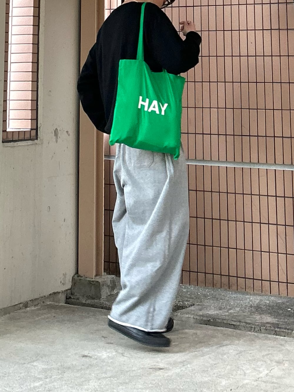 グレー系のスウェットパンツ、ブラック系のスニーカー、グリーン系のトートバッグを着用したメンズの春コーディネートの3枚目の写真