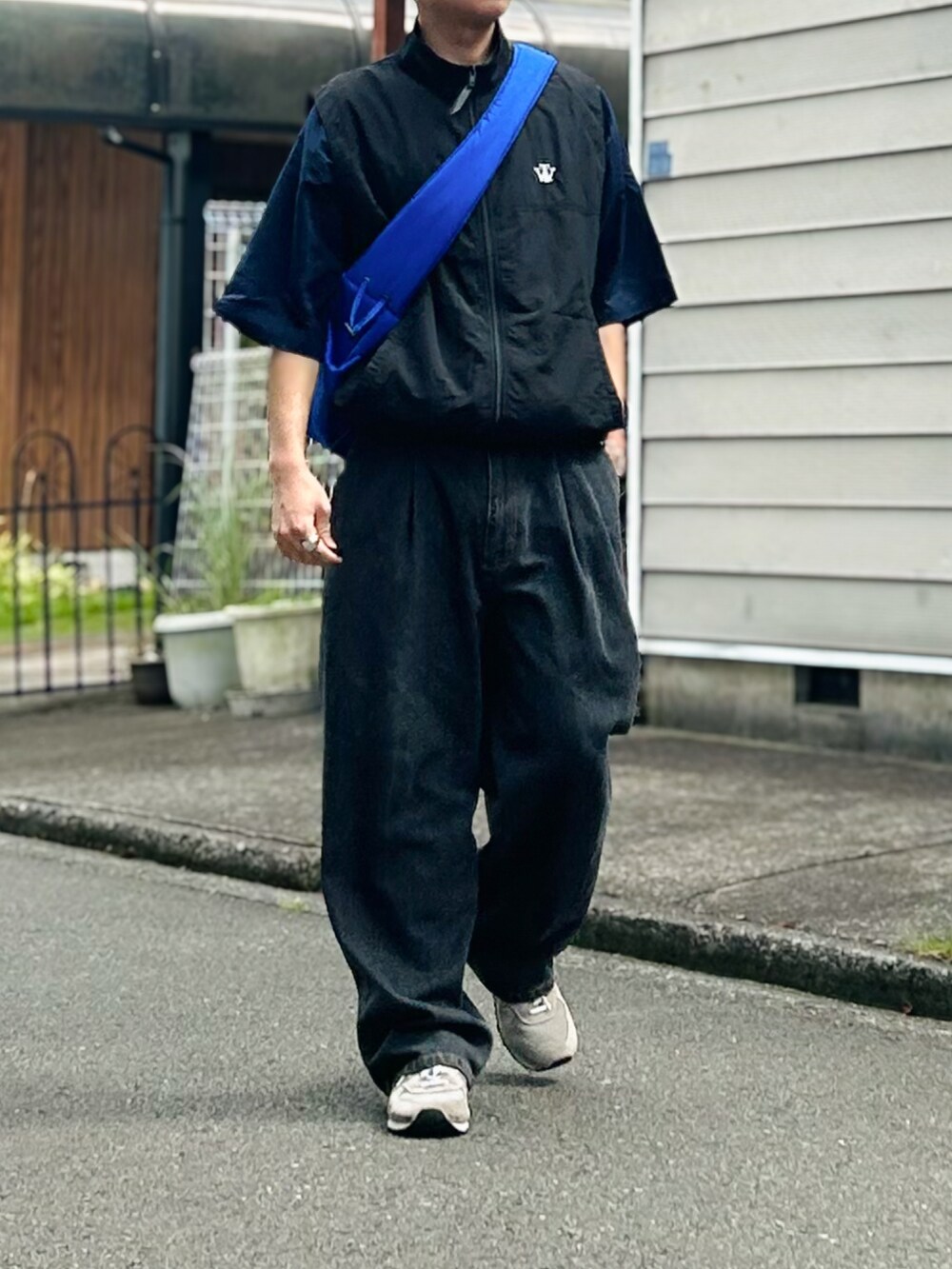 ブルー系のショルダーバッグ、ブルー系のデニムパンツ、ホワイト系のスニーカーを着用したメンズの秋コーディネートの2枚目の写真
