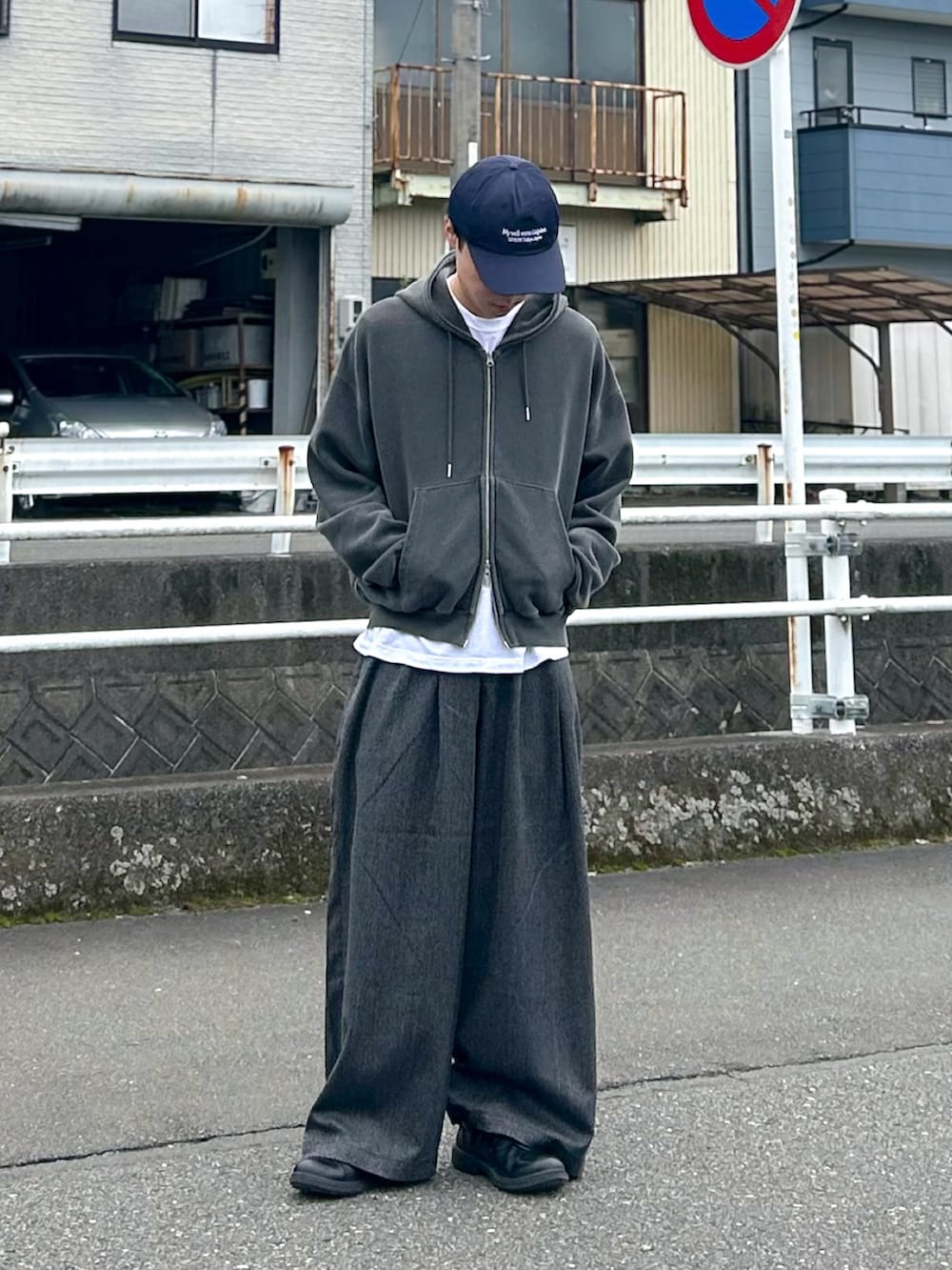 グレー系のパーカー、ブラック系のスラックス、ブラック系のシューズを着用したメンズの秋コーディネートの3枚目の写真