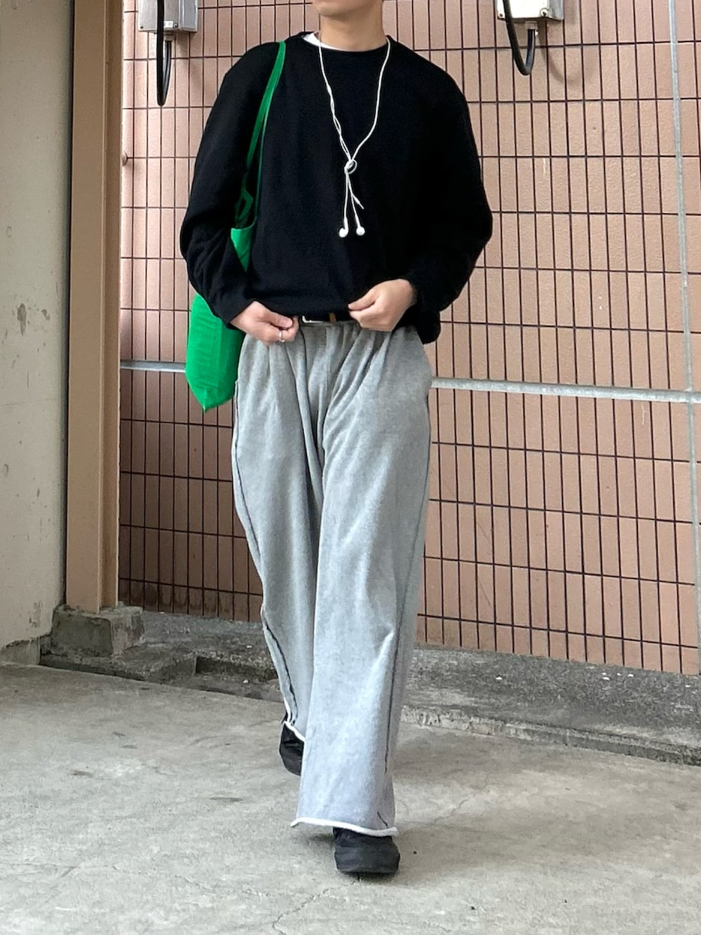 グレー系のスウェットパンツ、ブラック系のスニーカー、グリーン系のトートバッグを着用したメンズの春コーディネートの2枚目の写真