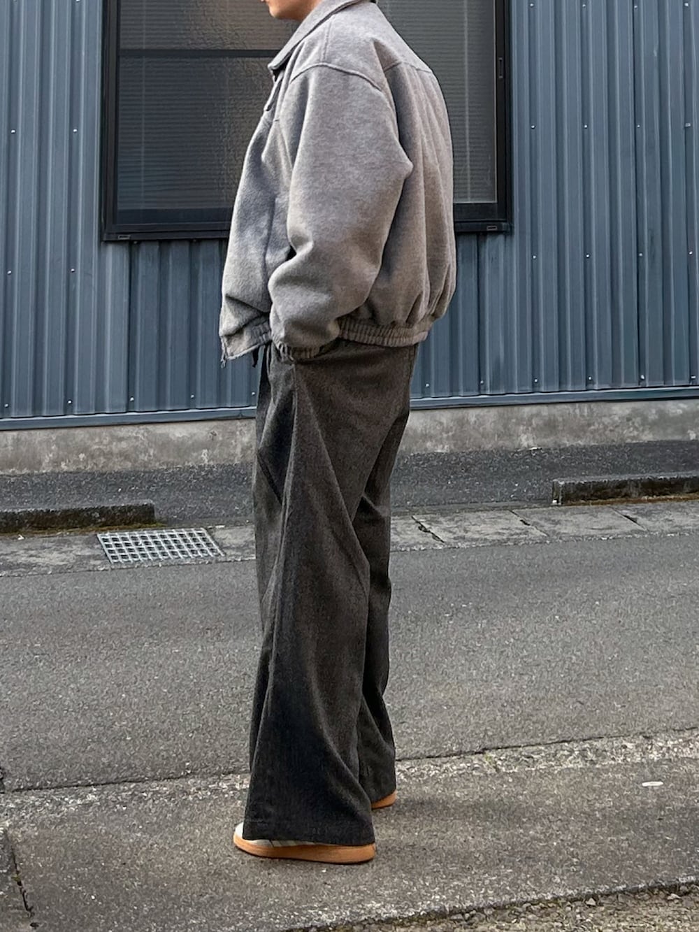 グレー系のブルゾン、グレー系のニット/セーター、ブラック系のスラックスを着用したメンズの冬コーディネートの3枚目の写真