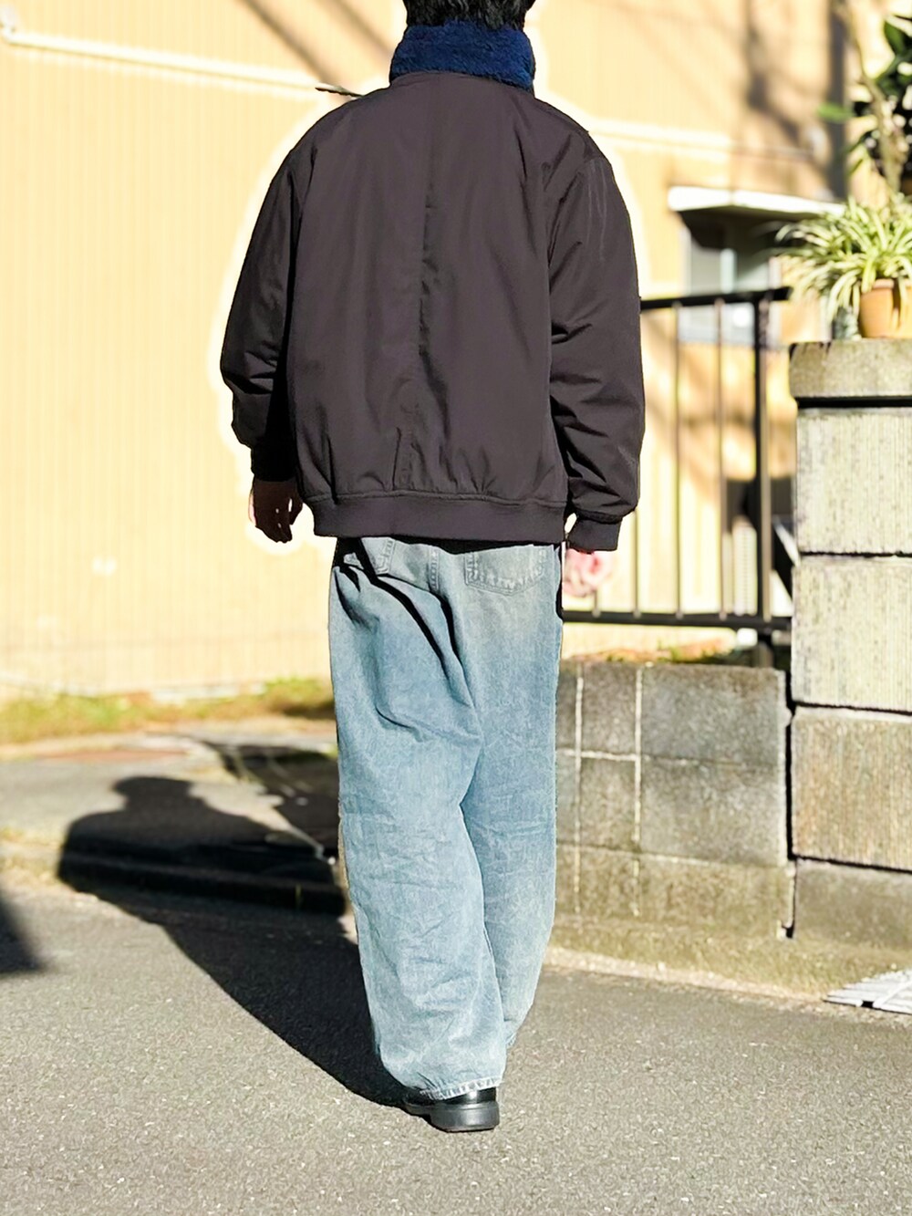 ブラック系のニット/セーター、ブルー系のデニムパンツ、ブラック系のシューズを着用したメンズの秋コーディネートの4枚目の写真