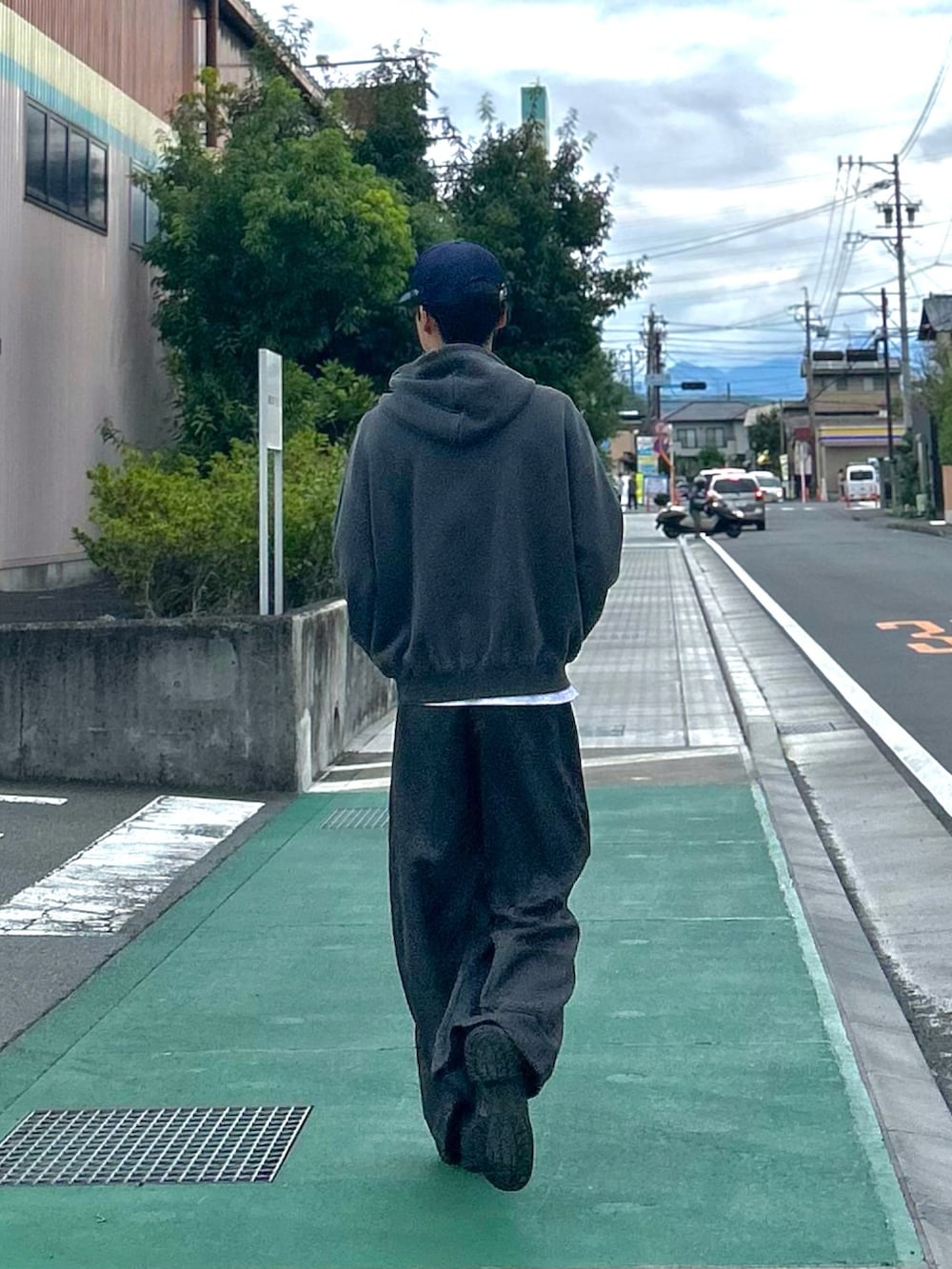 グレー系のパーカー、ブラック系のスラックス、ブラック系のシューズを着用したメンズの秋コーディネートの2枚目の写真