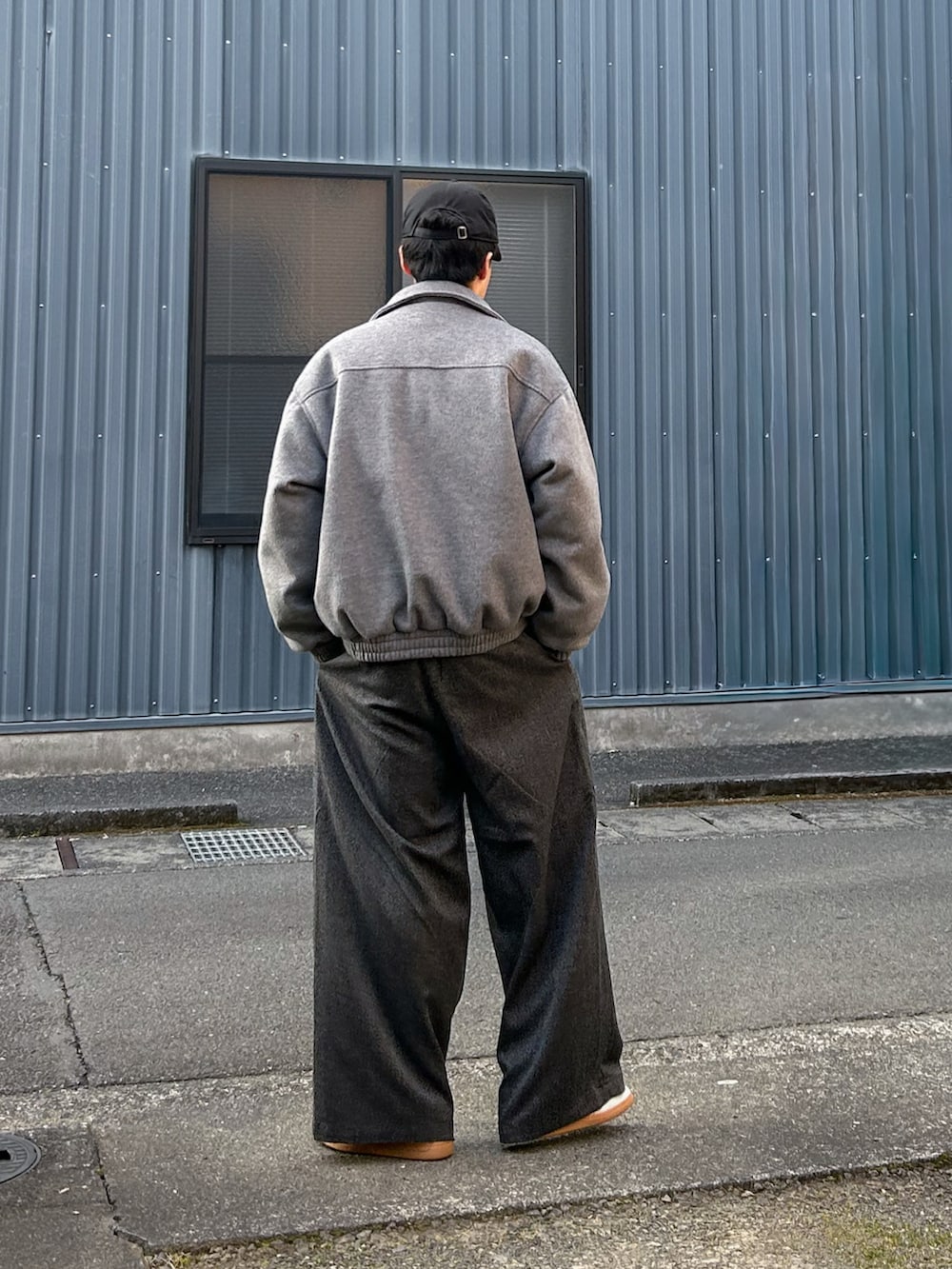 グレー系のブルゾン、グレー系のニット/セーター、ブラック系のスラックスを着用したメンズの冬コーディネートの4枚目の写真