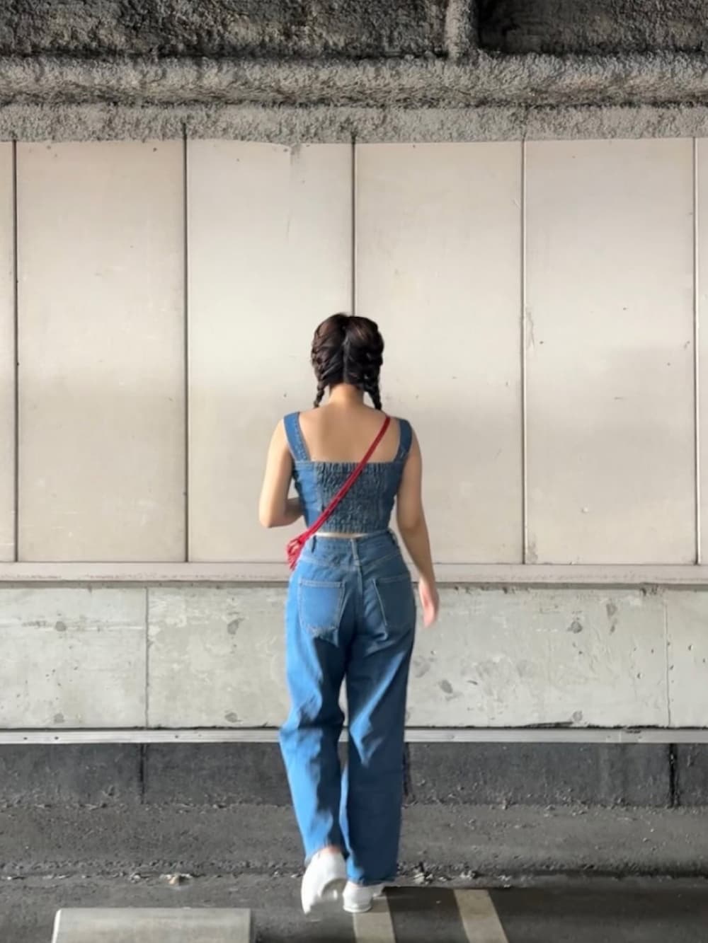 ブルー系のデニムパンツ、レッド系のショルダーバッグ、ホワイト系のサンダルを着用したレディースの夏コーディネートの2枚目の写真