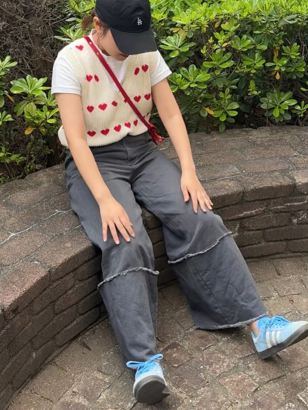 ホワイト系のニット/セーター、グレー系のデニムパンツ、レッド系のショルダーバッグを着用したレディースの春コーディネートの3枚目の写真