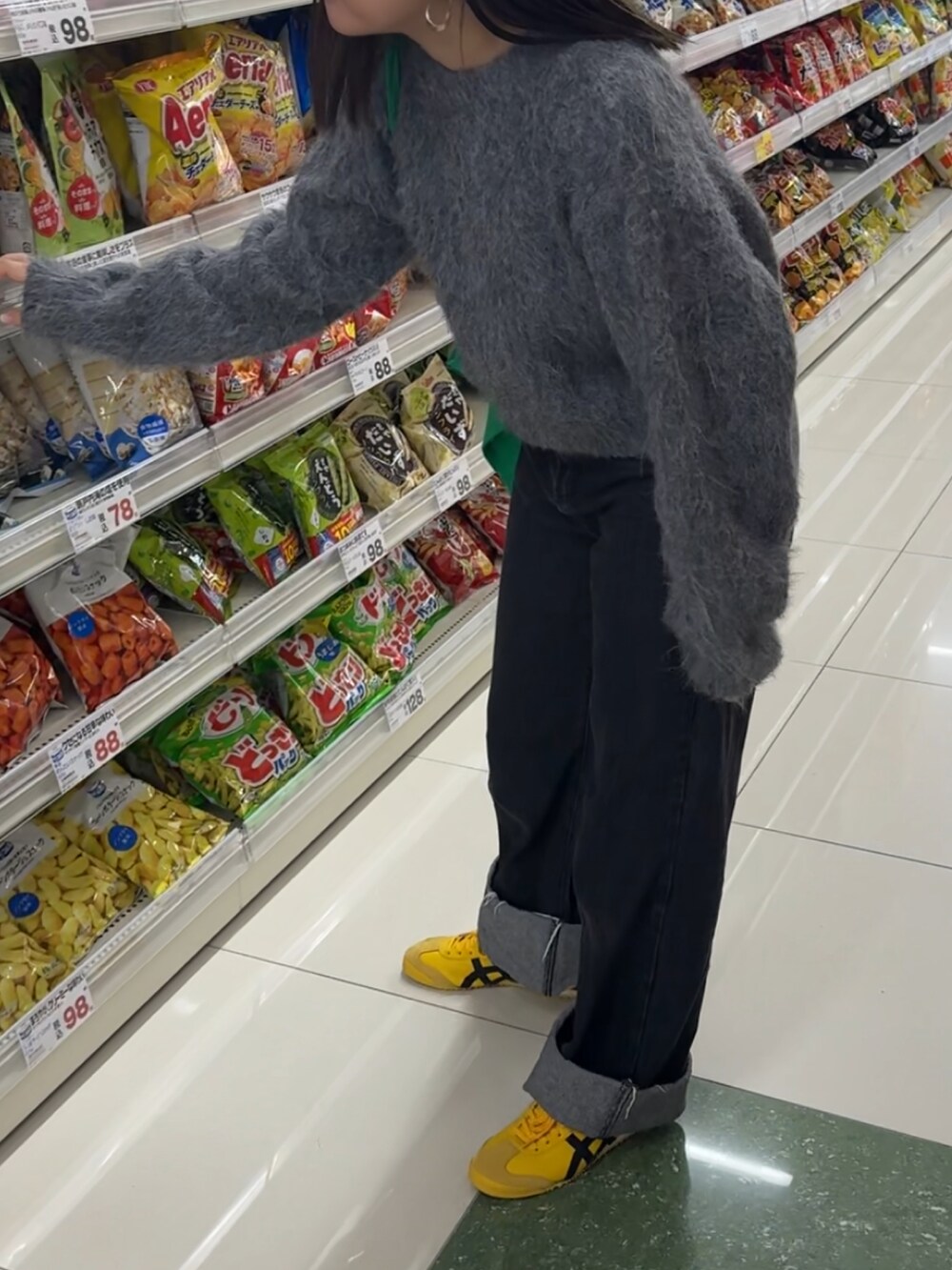 グレー系のニット/セーター、ブルー系のデニムパンツ、イエロー系のスニーカーを着用したレディースの秋コーディネートの2枚目の写真