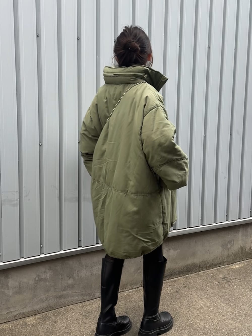 グリーン系のブルゾン、ブラック系のブーツ、オレンジ系のショルダーバッグを着用したレディースの冬コーディネートの2枚目の写真