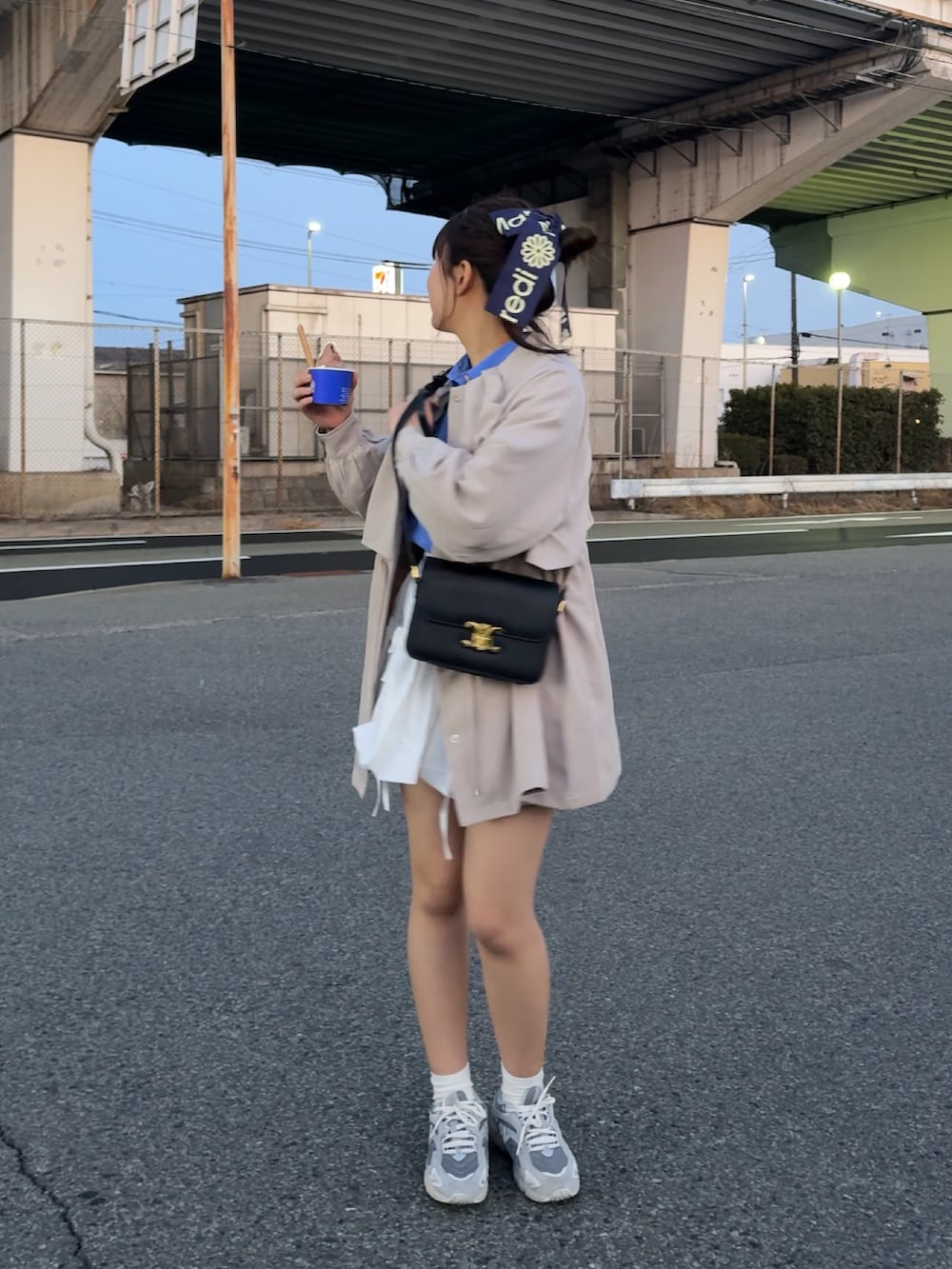 ホワイト系のトレンチコート、ブラック系のショルダーバッグ、シルバー系のスニーカーを着用したレディースの春コーディネートの2枚目の写真