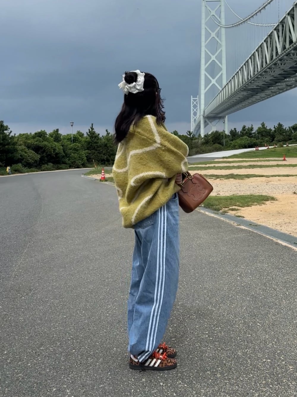 グリーン系のニット/セーター、ブルー系のデニムパンツを着用したレディースの秋コーディネートの2枚目の写真