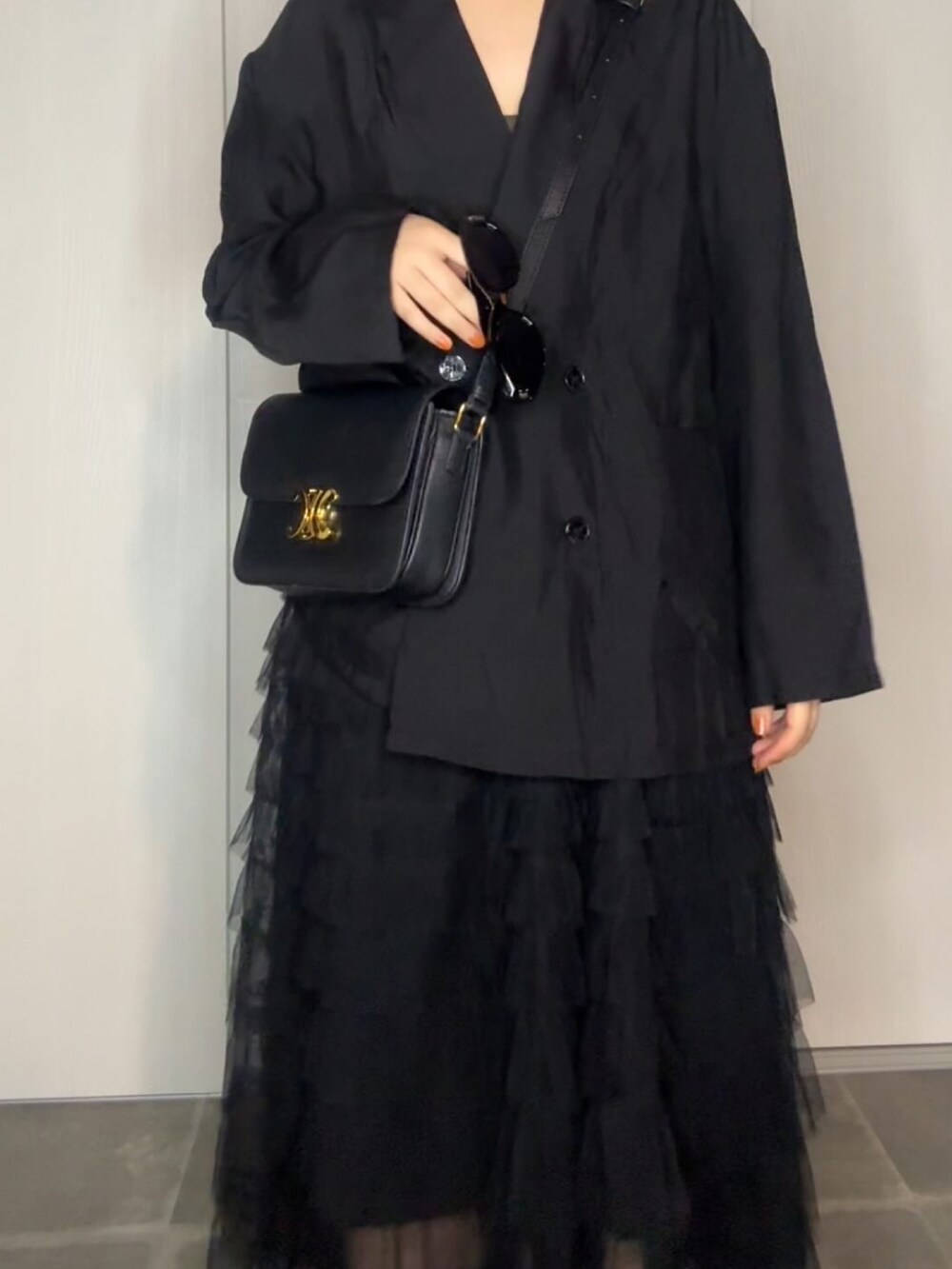 ブラック系のテーラードジャケット、ブラック系のショルダーバッグ、ブラック系のサングラスを着用したレディースの春コーディネートの2枚目の写真