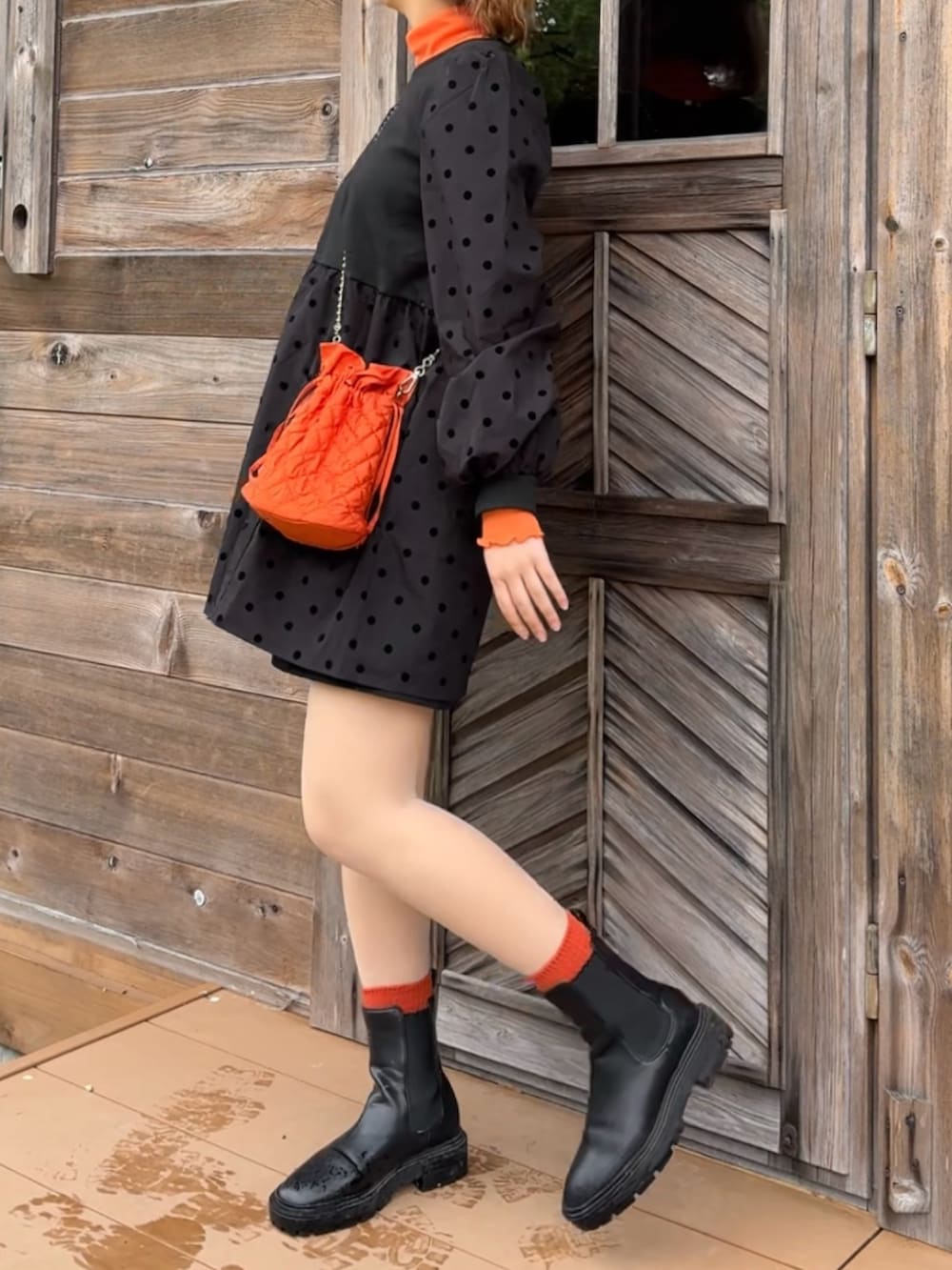 オレンジ系のショルダーバッグ、ブラック系のブーツ、ブラック系のその他パンツを着用したレディースの春コーディネートの2枚目の写真