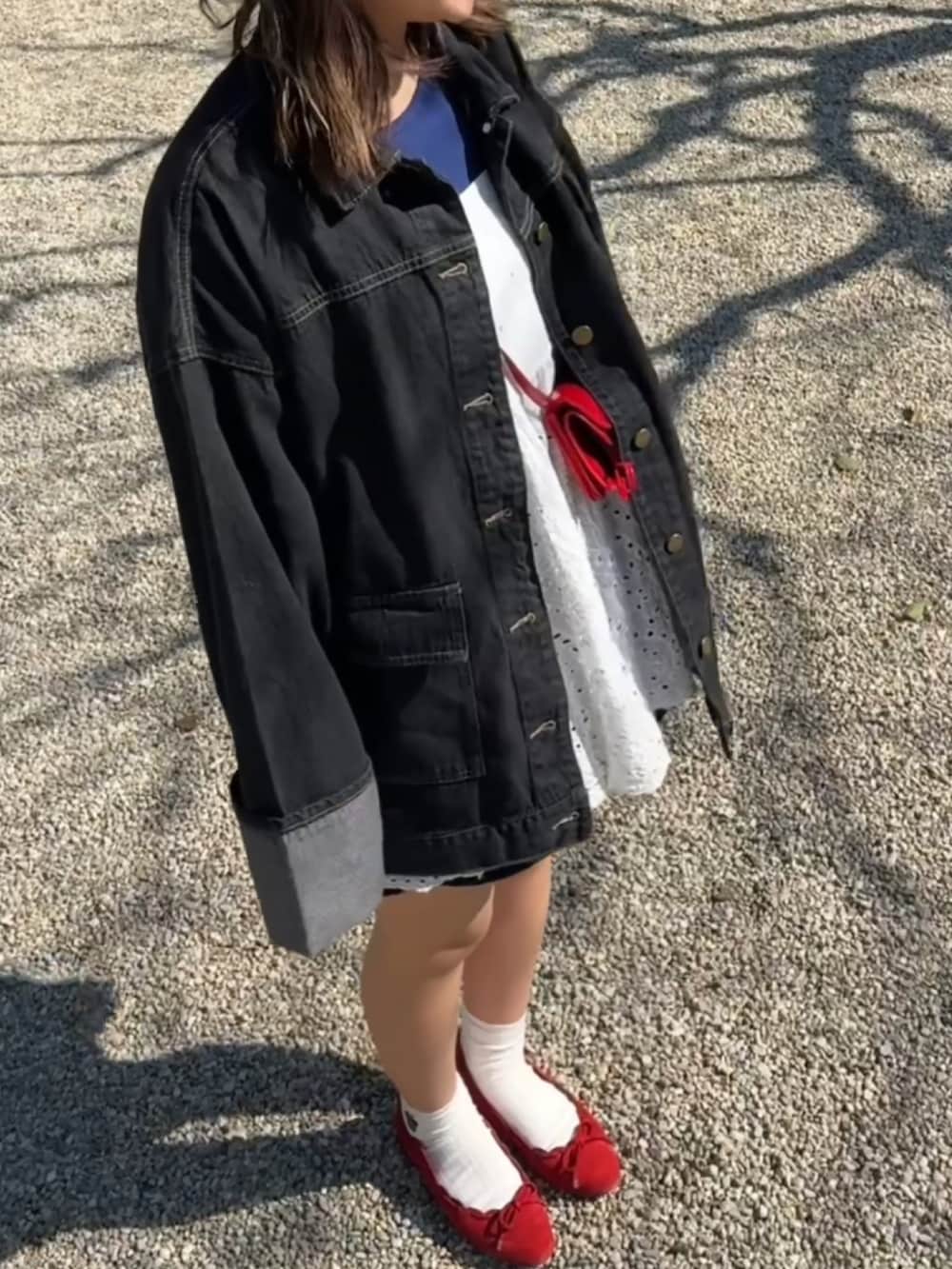 レッド系のショルダーバッグ、ブルー系のパンプス、ブラック系のデニムジャケットを着用したレディースの春コーディネートの3枚目の写真