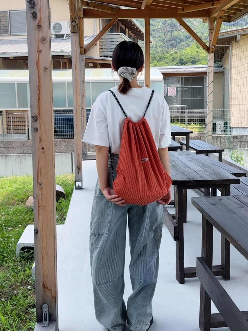 ホワイト系のTシャツ/カットソー、オレンジ系のショルダーバッグ、ブラック系のサンダルを着用したレディースの夏コーディネートの2枚目の写真