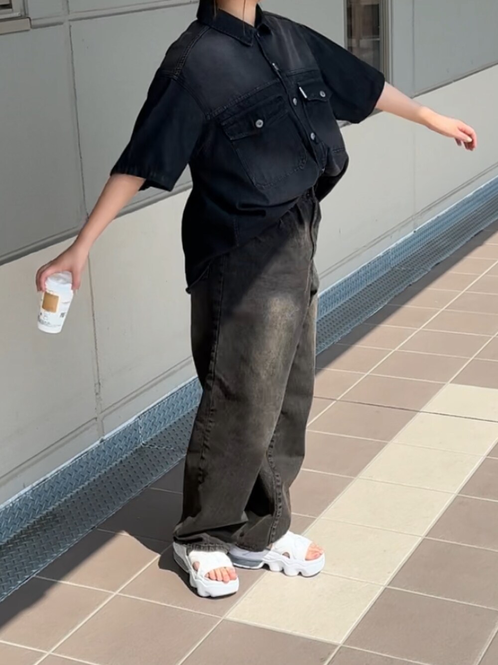 ブラック系のデニムパンツ、ブラック系のシャツ/ブラウス、ホワイト系のサンダルを着用したレディースの春コーディネートの2枚目の写真