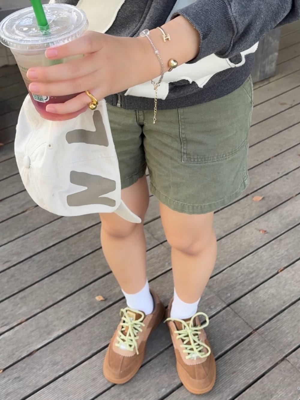 グレー系のパーカー、ベージュ系のスニーカー、ホワイト系のキャップを着用したレディースの夏コーディネートの3枚目の写真