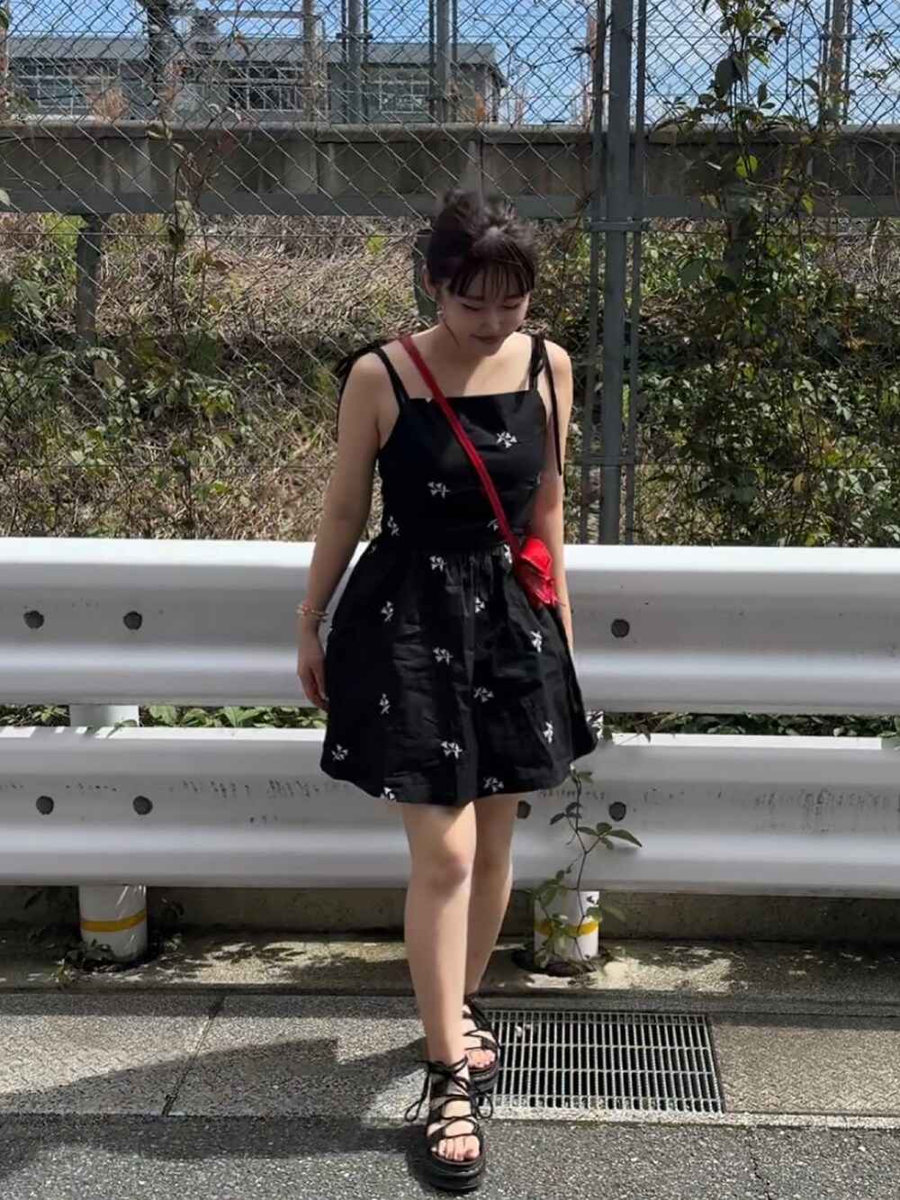 レッド系のショルダーバッグ、ブラック系のサンダルを着用したレディースの夏コーディネートの2枚目の写真