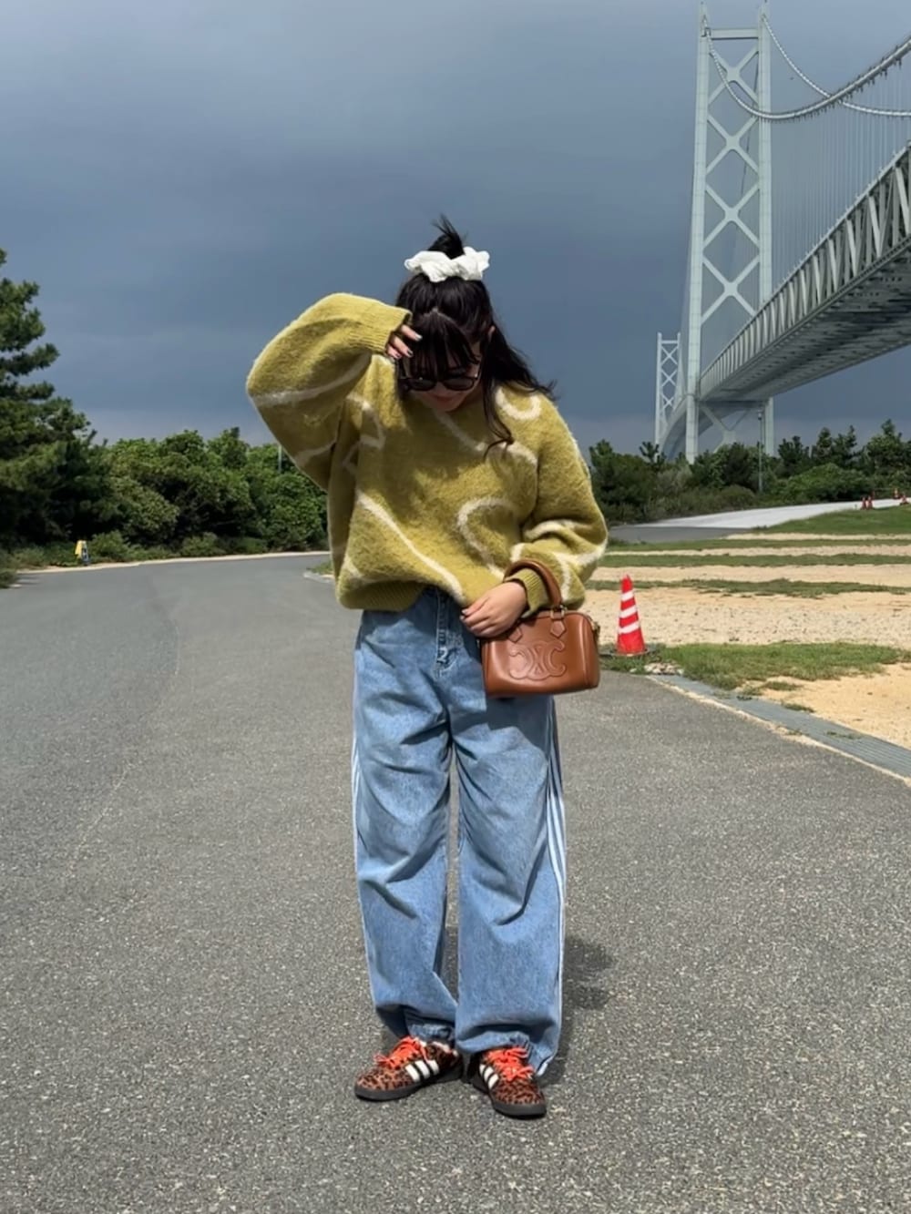 グリーン系のニット/セーター、ブルー系のデニムパンツを着用したレディースの秋コーディネートの3枚目の写真