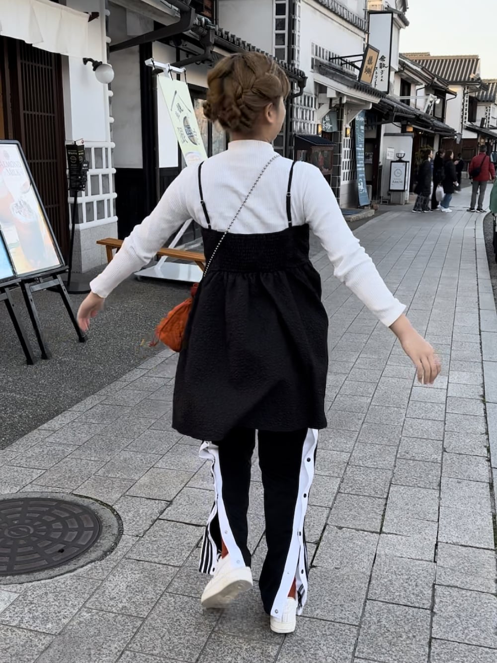 ブラック系のその他パンツ、オレンジ系のショルダーバッグ、ホワイト系のニット/セーターを着用したレディースの春コーディネートの2枚目の写真