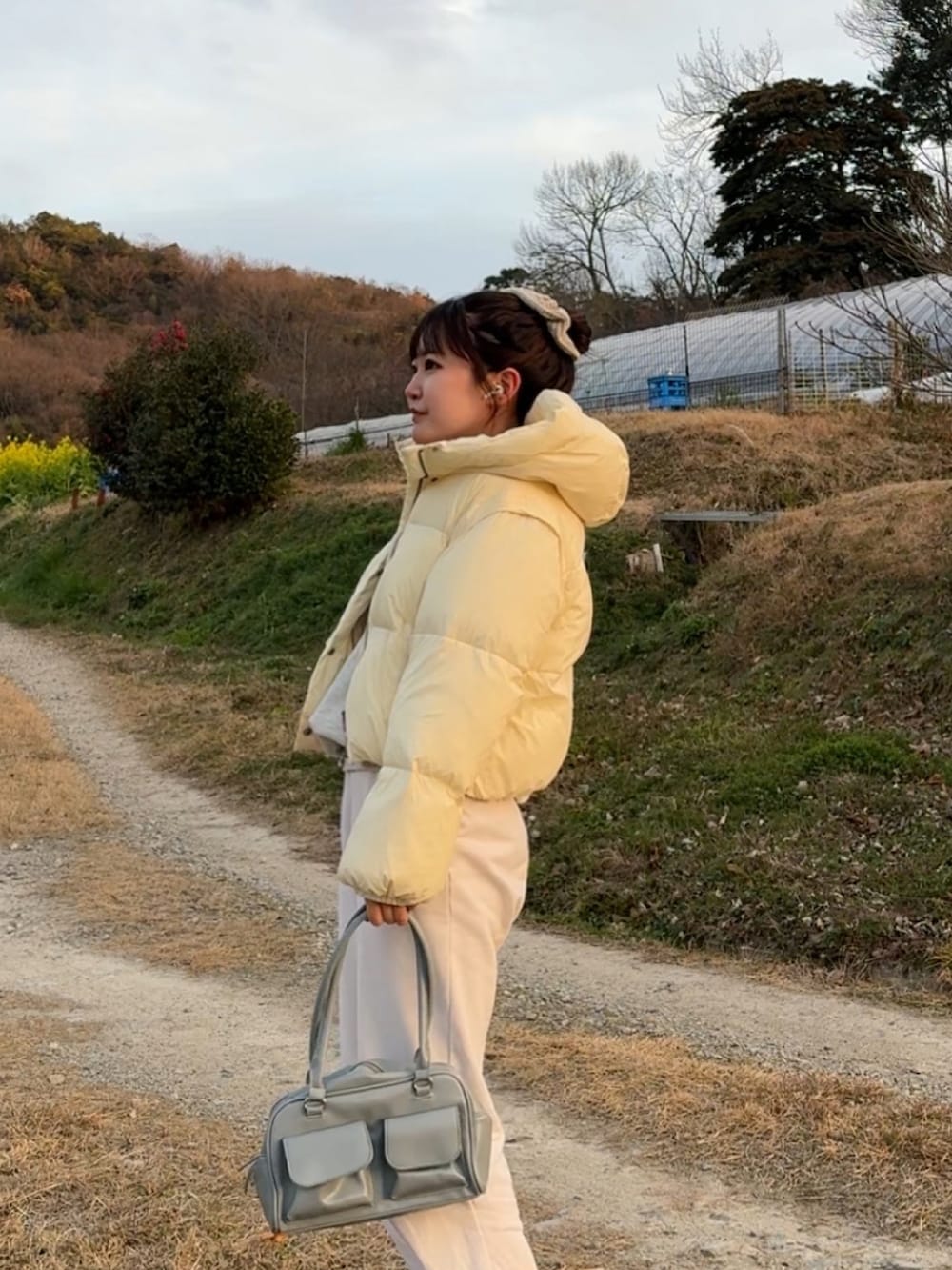 ホワイト系のダウンジャケット/コート、ブルー系のハンドバッグ、ホワイト系のスウェットパンツを着用したレディースの冬コーディネートの2枚目の写真