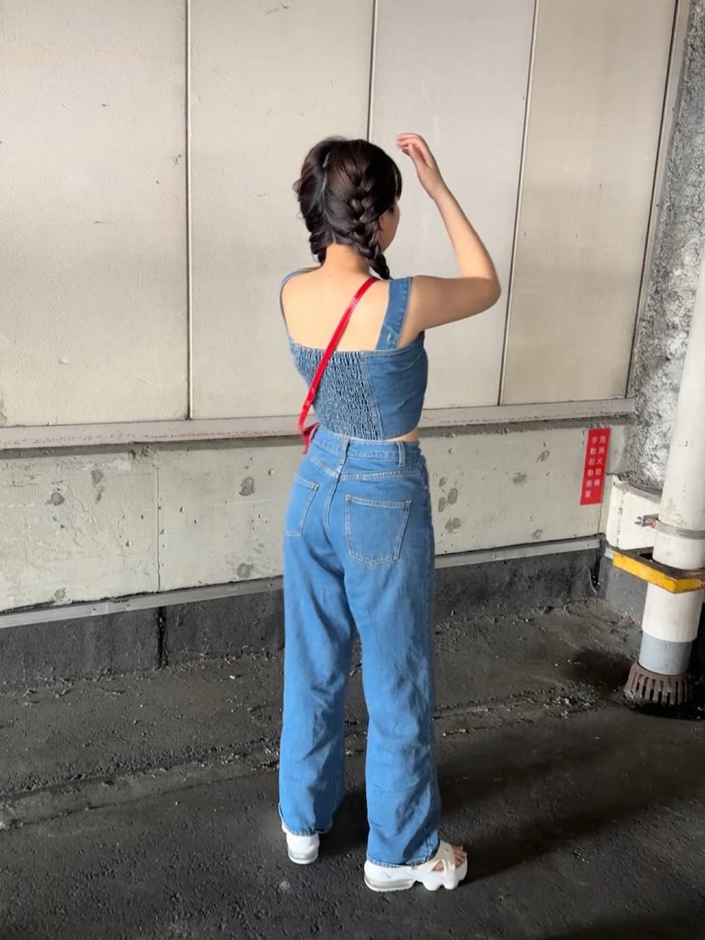 ブルー系のデニムパンツ、レッド系のショルダーバッグ、ホワイト系のサンダルを着用したレディースの夏コーディネートの4枚目の写真
