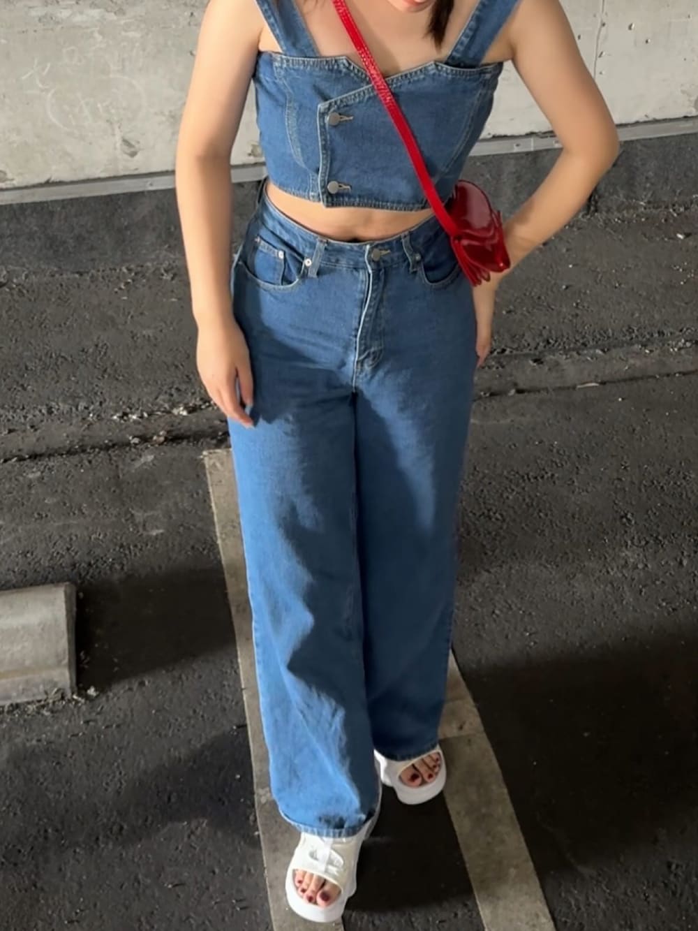 ブルー系のデニムパンツ、レッド系のショルダーバッグ、ホワイト系のサンダルを着用したレディースの夏コーディネートの3枚目の写真