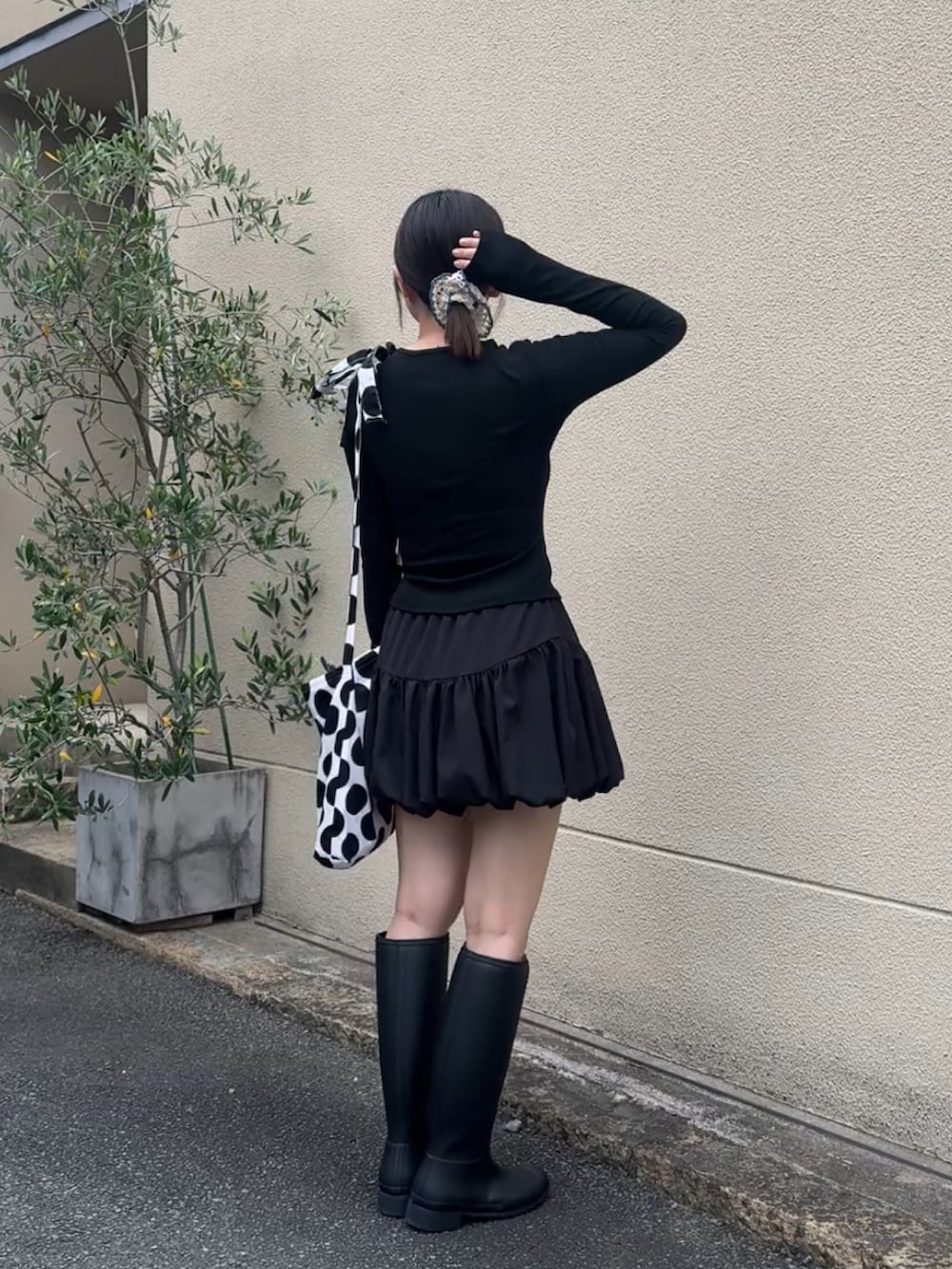 ブラック系のレインシューズ、ブラック系のスカート、ホワイト系のショルダーバッグを着用したレディースの夏コーディネートの5枚目の写真